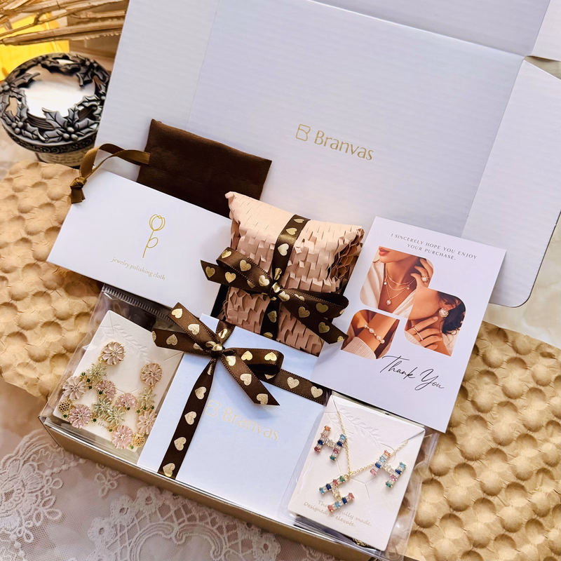 Branvas jewelry gift box with a brown heart-patterned ribbon, containing earrings, necklace, jewelry polishing cloth, and thank you card.