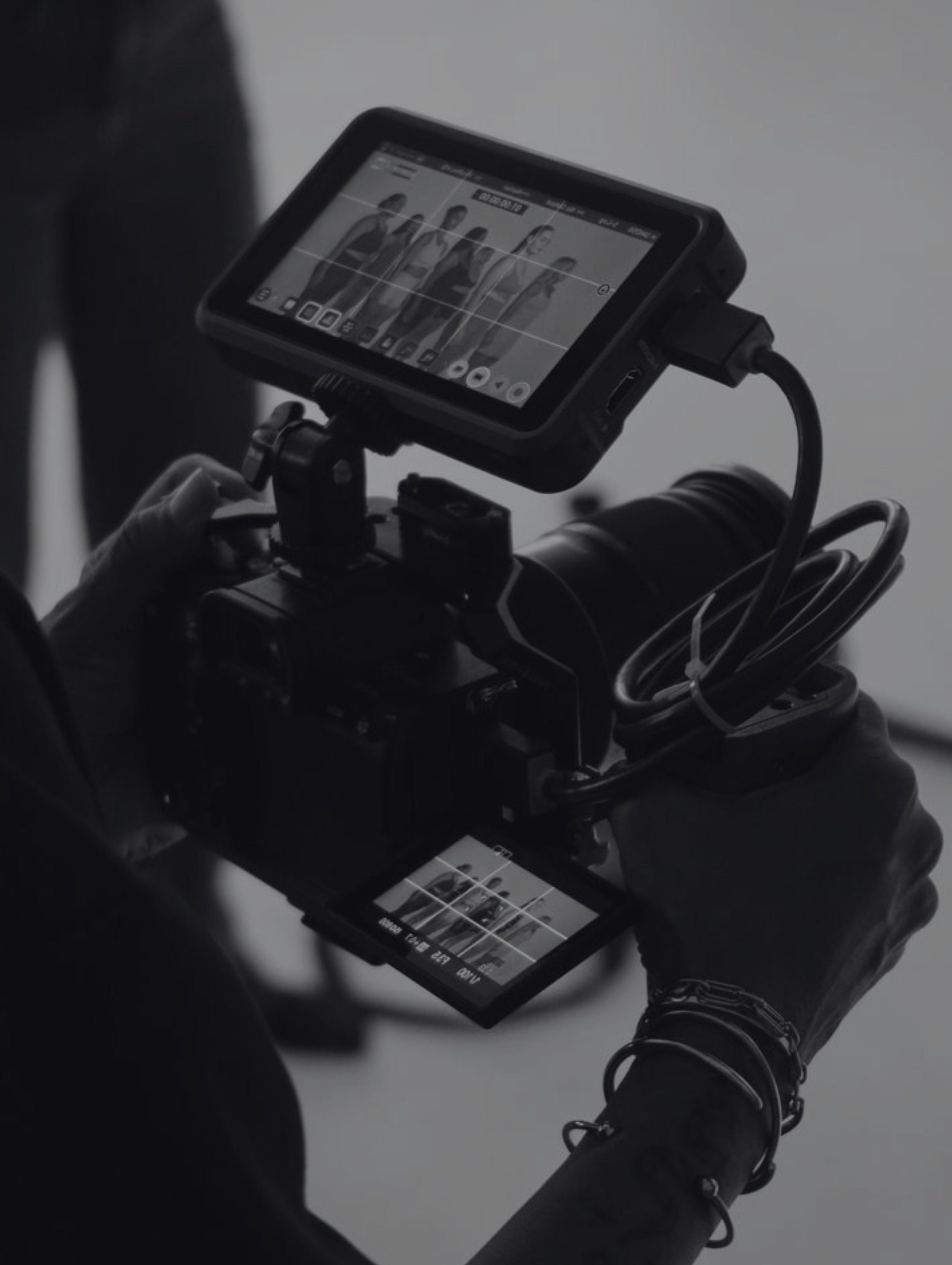 Person holding a camera with two screens showing a group of five people posing for a photo shoot.