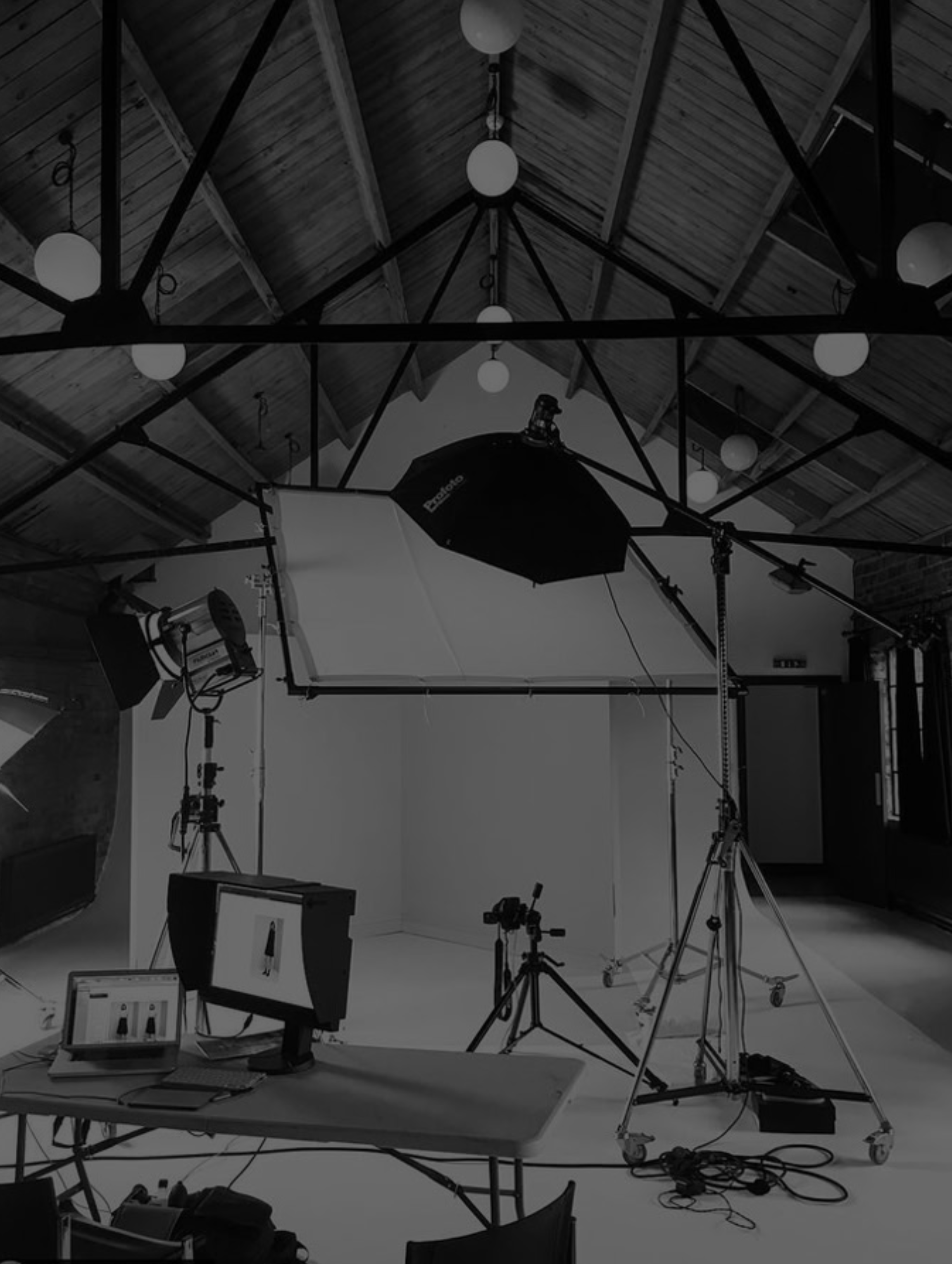 Interior of a professional photography studio with lighting equipment, cameras, and computer monitors.