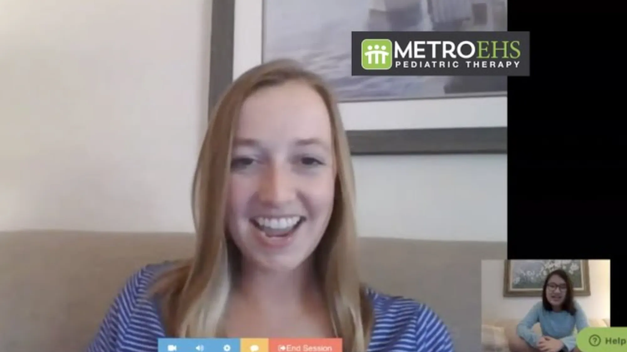 Video call screen showing a smiling woman with blonde hair in a blue striped shirt and a smaller inset of another woman with glasses and dark hair.