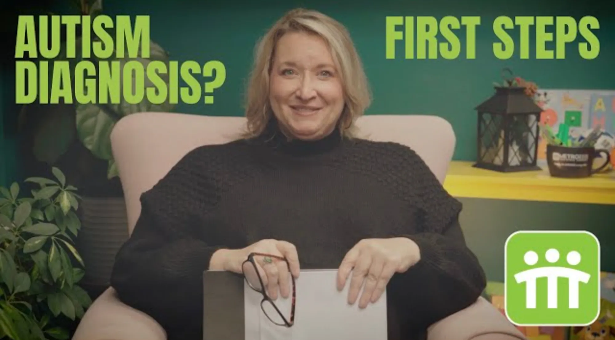 Woman sitting in a chair holding glasses and a clipboard with text 'AUTISM DIAGNOSIS? FIRST STEPS' around her and a green logo in the bottom right.