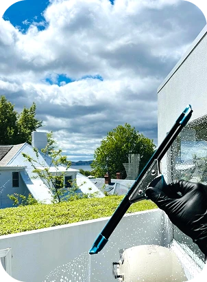 A person wearing black gloves is cleaning a window with a cloth, focusing on removing dirt and smudges.