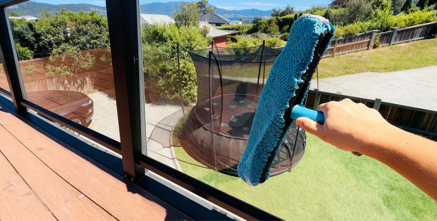 A person using a window cleaner to clean a large window, focused on removing dirt and streaks for a clear view.