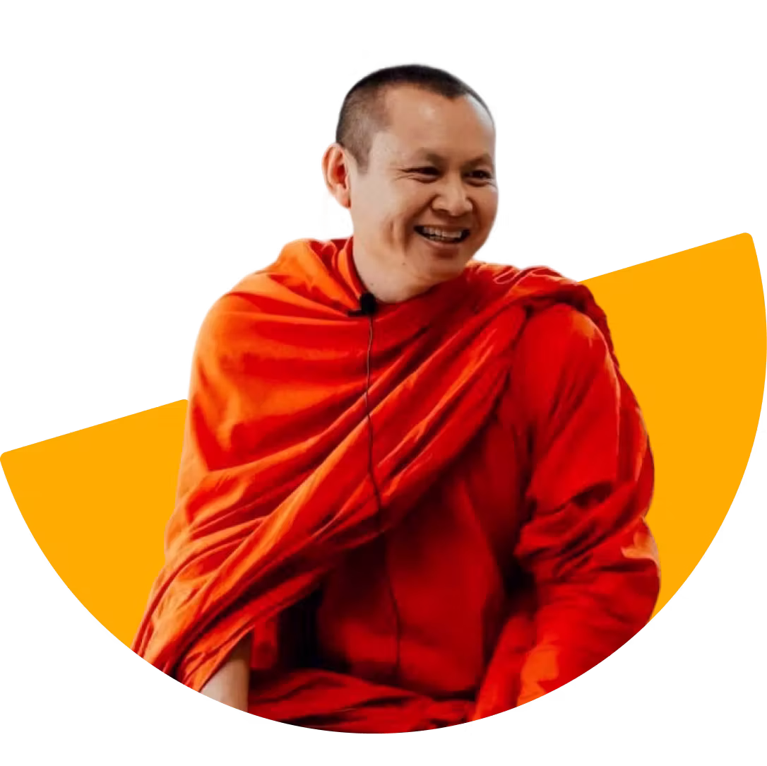 Smiling Buddhist monk wearing traditional orange robes against a black and orange semi-circular background.