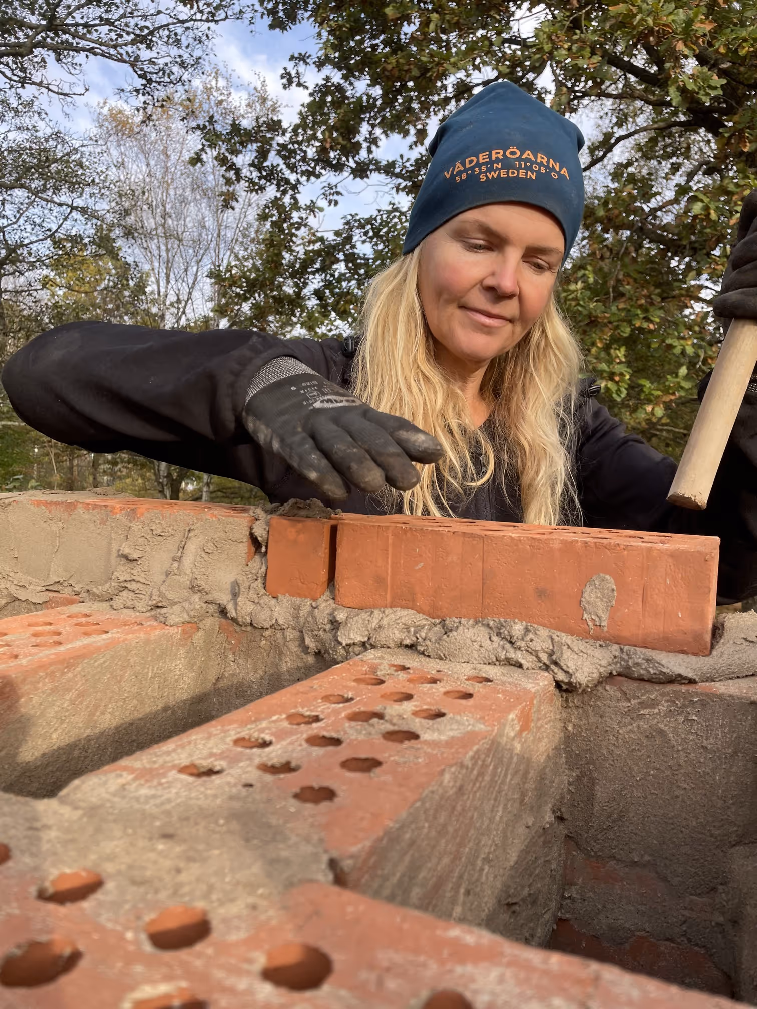 Person som arbetar med tegel under återuppbyggnad på Oliviagården