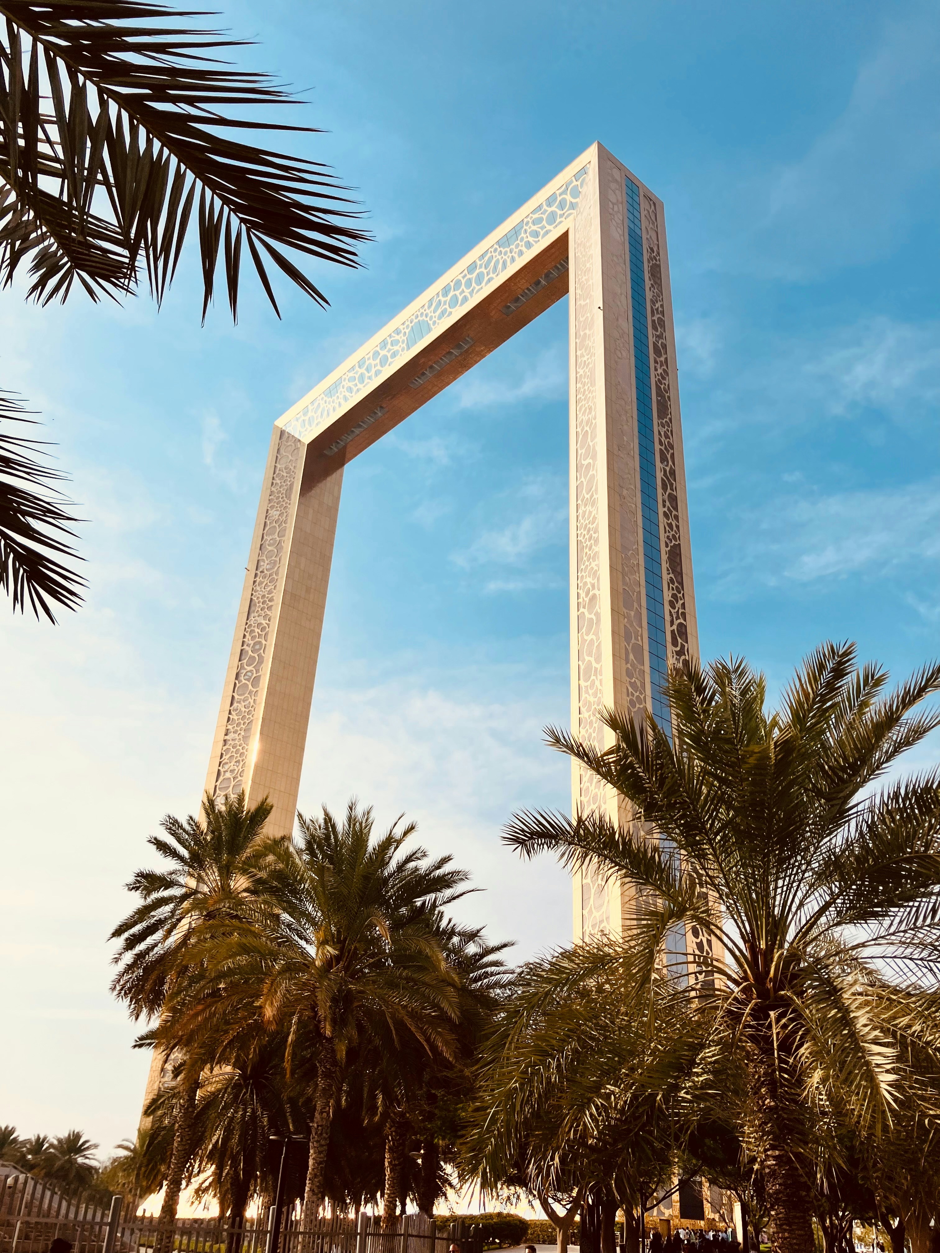 Cityscape at sunset featuring the Museum of the Future with Arabic calligraphy, Burj Khalifa, and the Al Yaqoub Tower in Dubai.