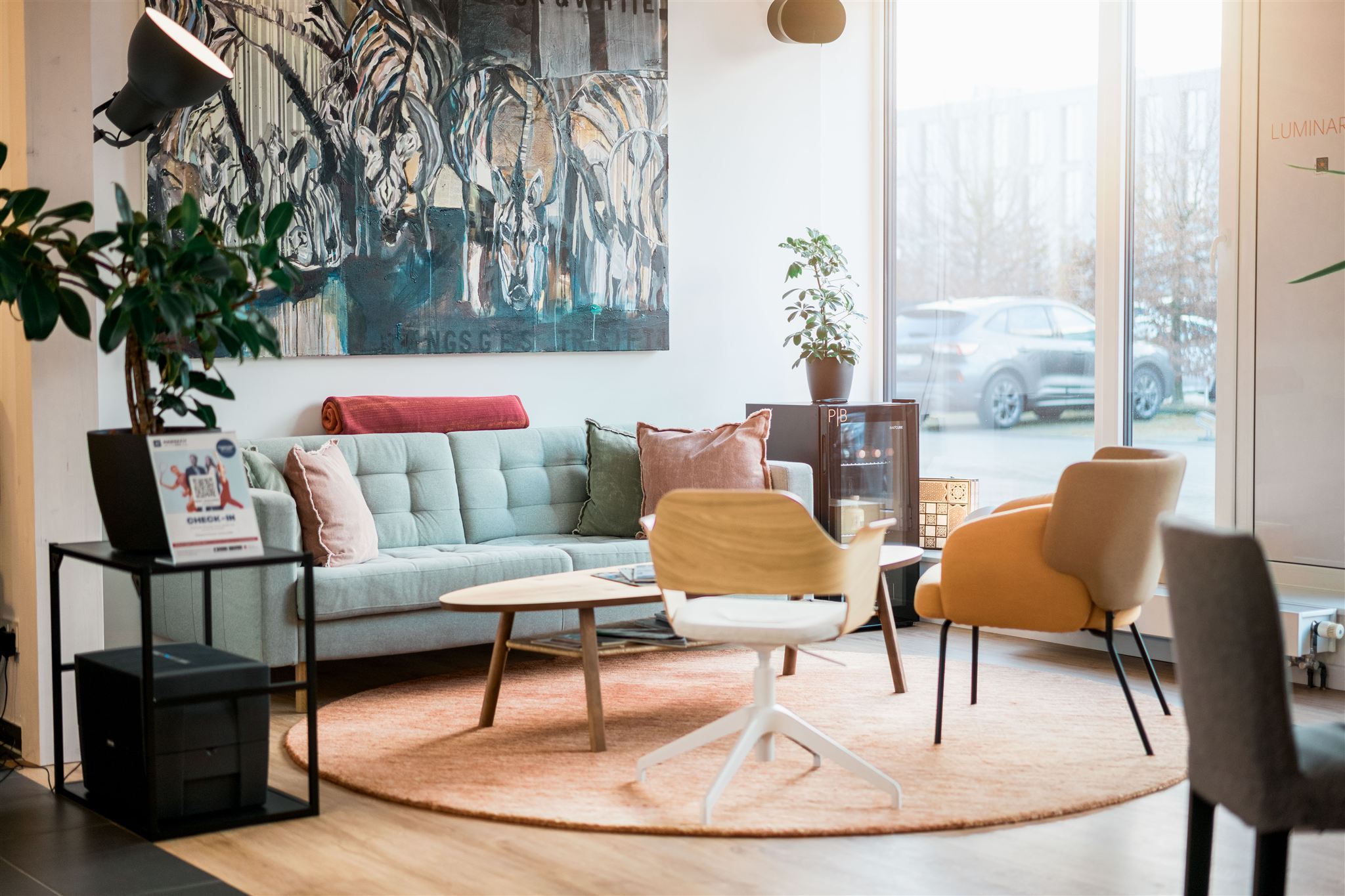 Der Wartebereich fotografiert mit einer gemütlichen Couch und einem farbigen Gemälde im Hintergrund.