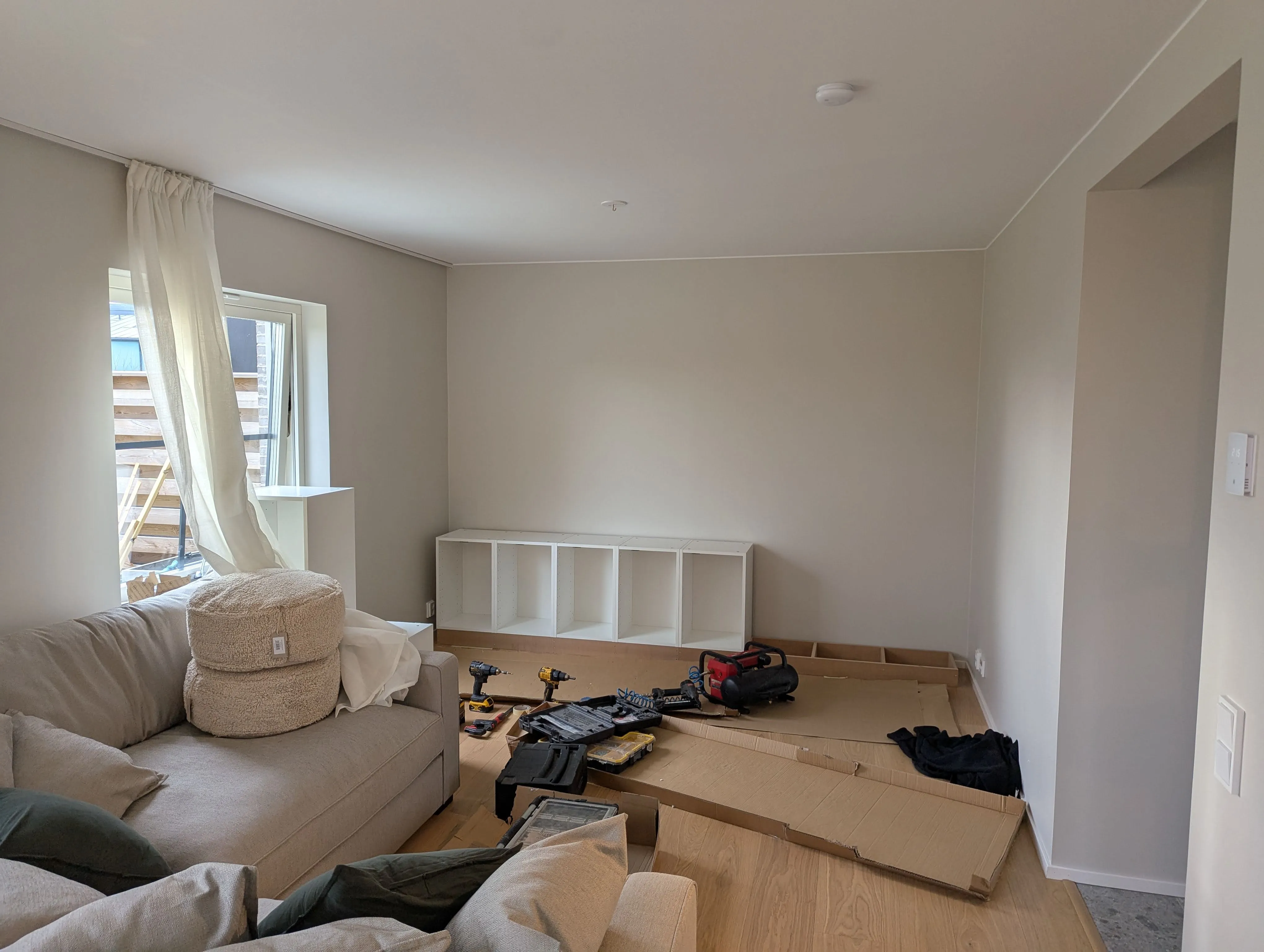 Snickeri av platsbyggd bokhylla i vardagsrum.