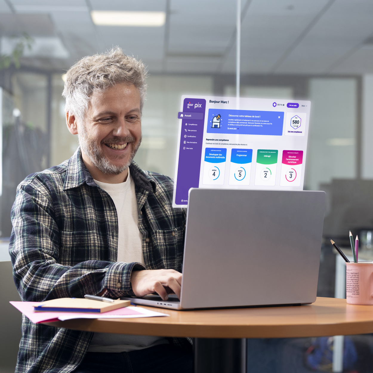 Homme souriant utilisant un ordinateur portable dans un bureau avec une interface PIX affichée au-dessus de l’écran.