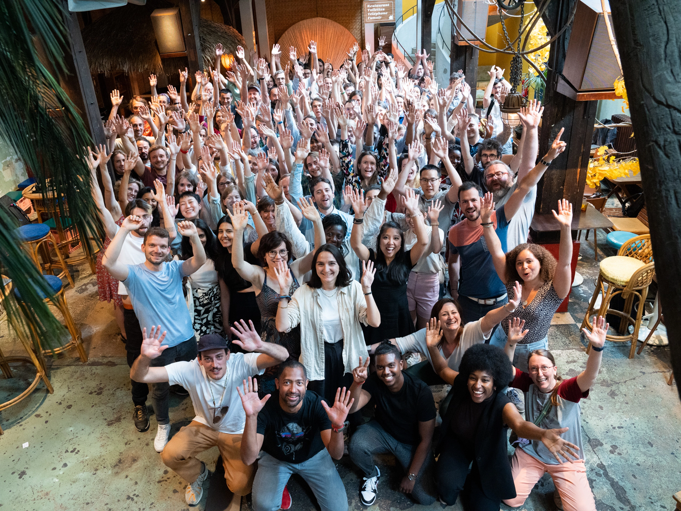 Personnes travaillant chez Pix levant les mains vers l'appareil photo dans un environnement intérieur convivial.