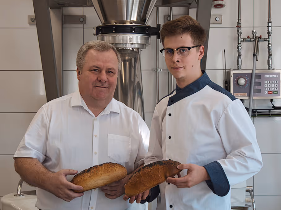 Dwóch mężczyzn trzymających świeżo upieczony chleb w piekarni.