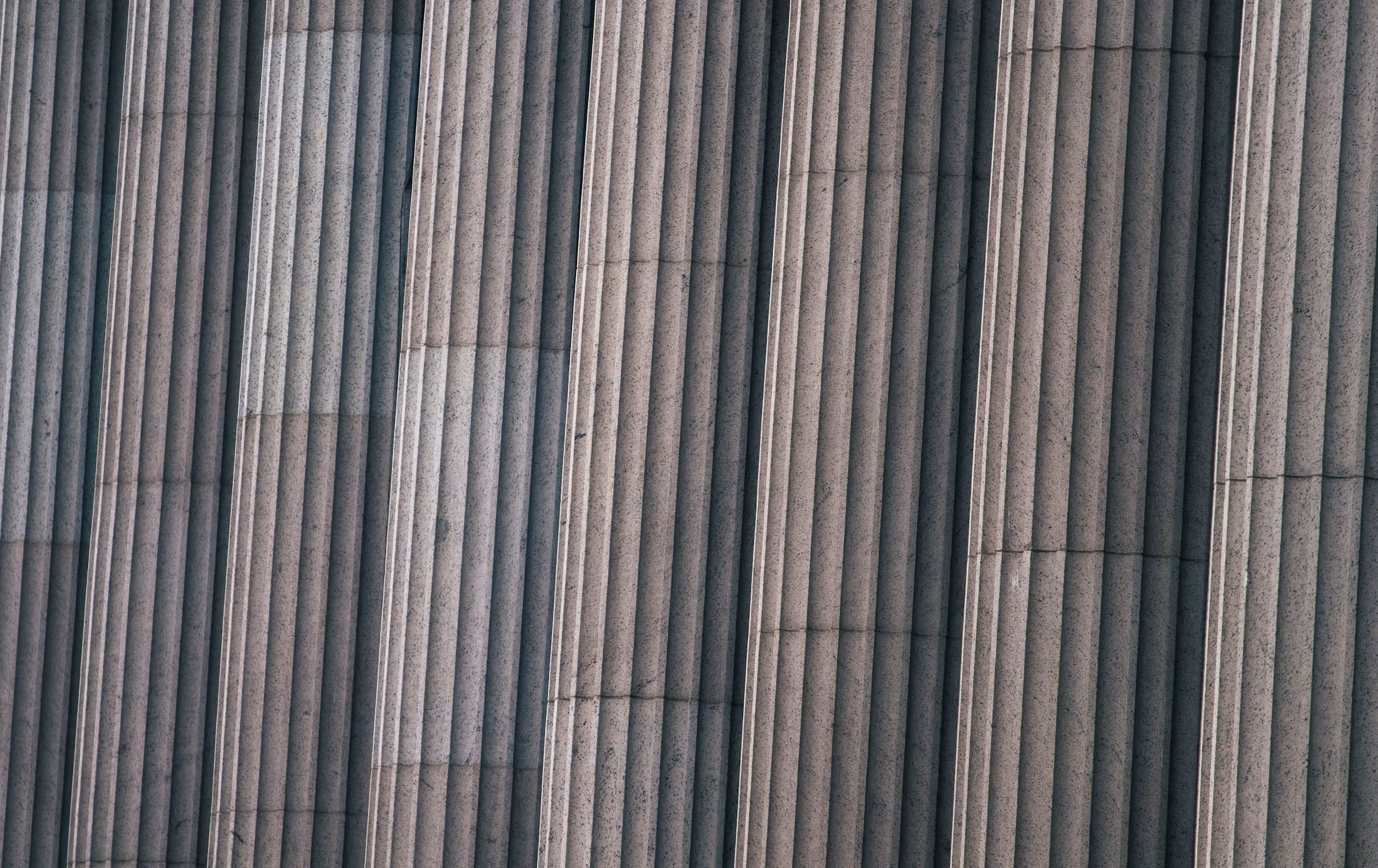 Close-up of tall, fluted stone columns with vertical grooves and light shading.