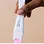 A hand holding a white pregnancy test stick with a pink indicator against a light beige background.