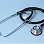 A black stethoscope with a silver chest piece resting on a light blue surface.