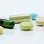 A variety of colorful tablets and capsules scattered on a white surface, including green, yellow, blue, and beige shapes.