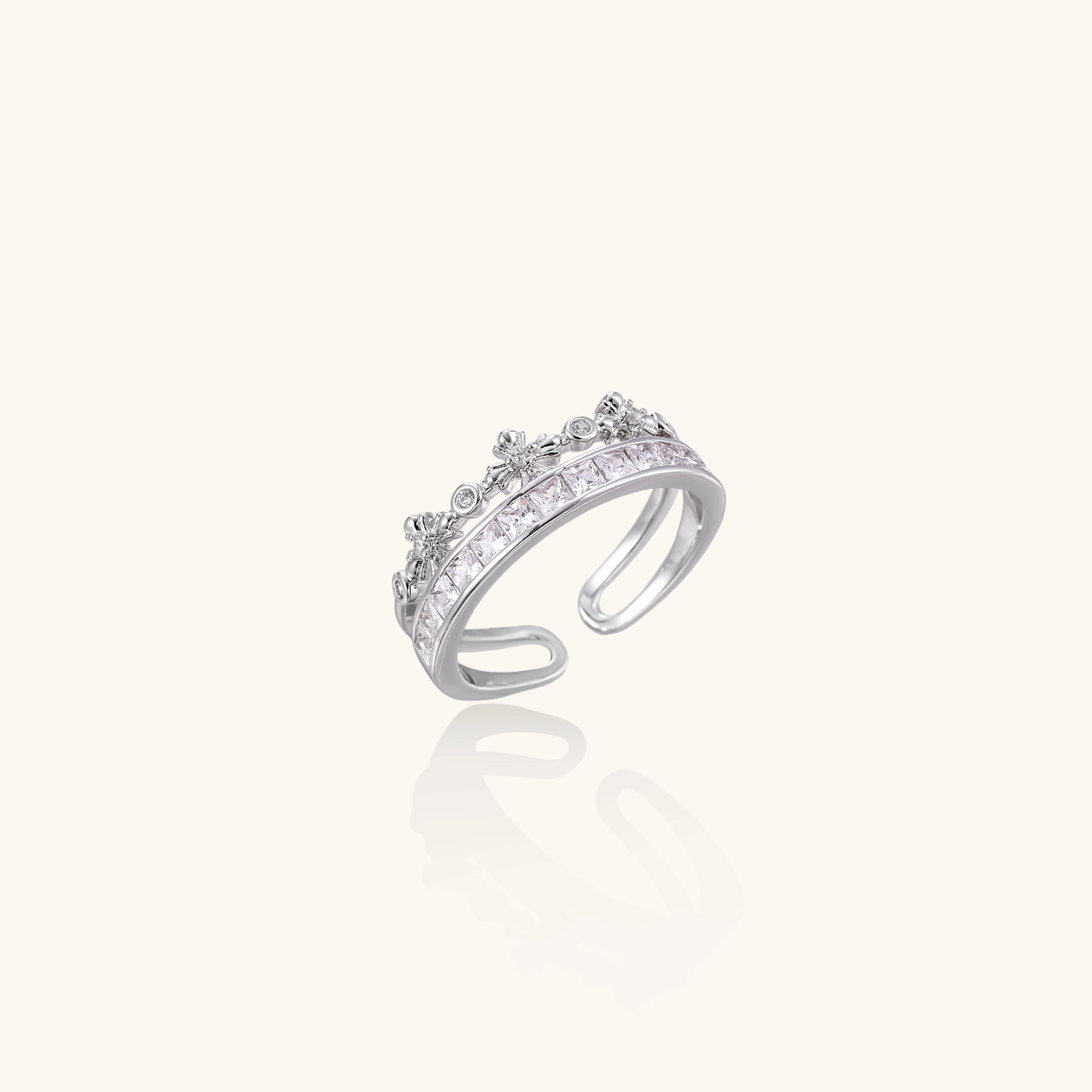Silver-toned adjustable crown ring with channel-set square zirconia stones and delicate floral details on white background