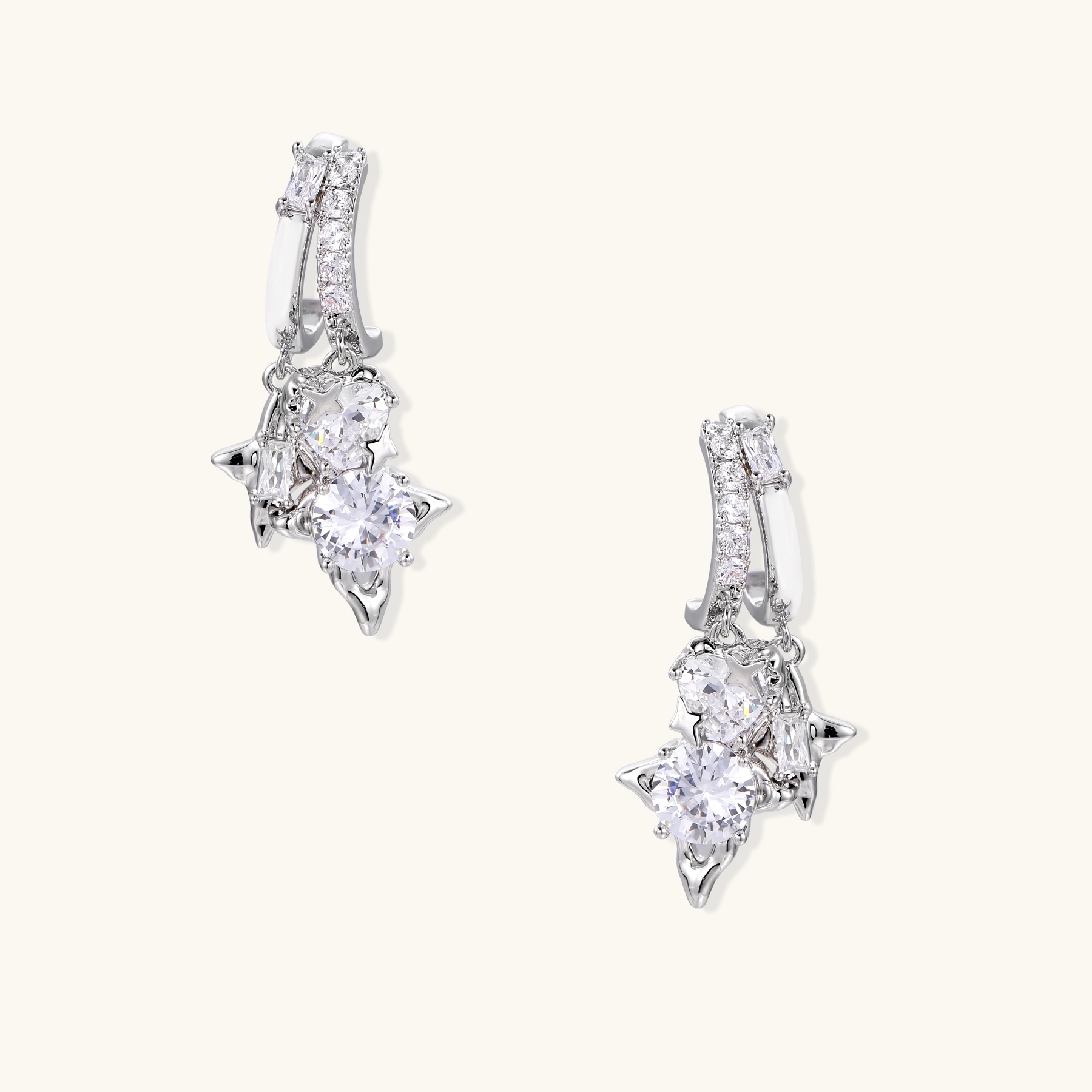 White gold-plated huggie earrings with geometric emerald-cut zirconia clusters in starburst formation on beige background