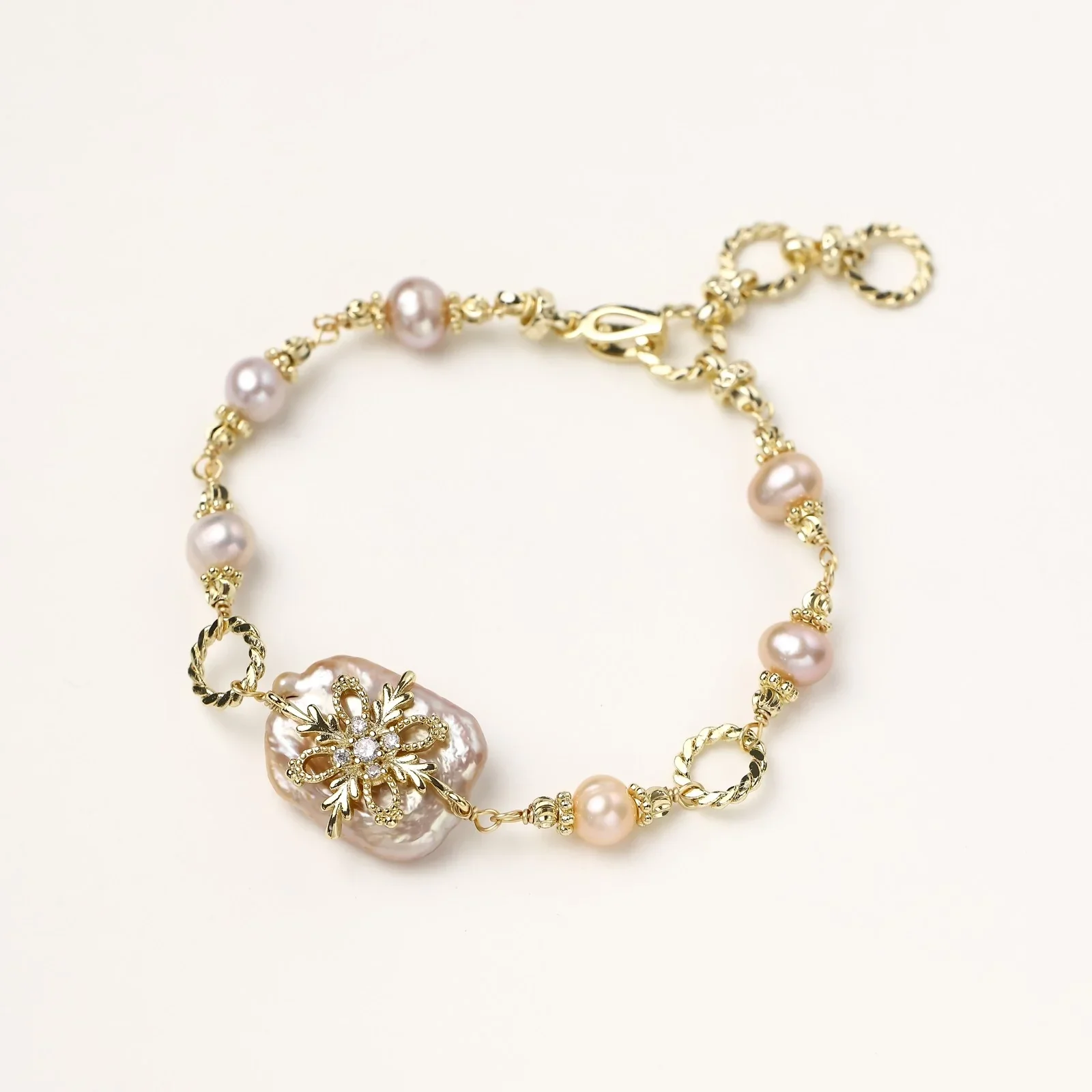 Gold-plated bracelet with pink baroque pearl centerpiece, floral connector, and freshwater pearls