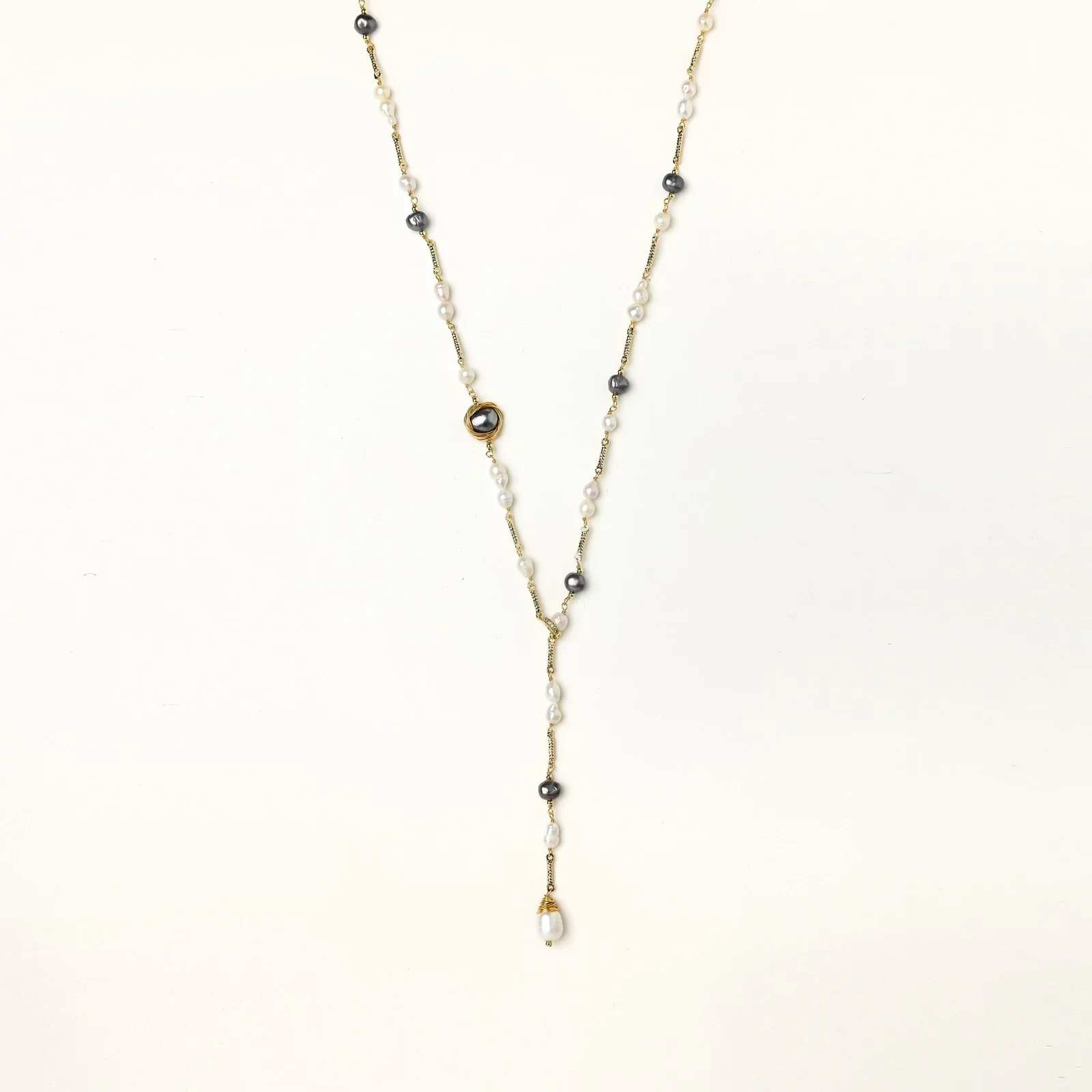 Y-shaped gold-plated necklace with white and gray freshwater pearls on cream background, showing adjustable drop design.