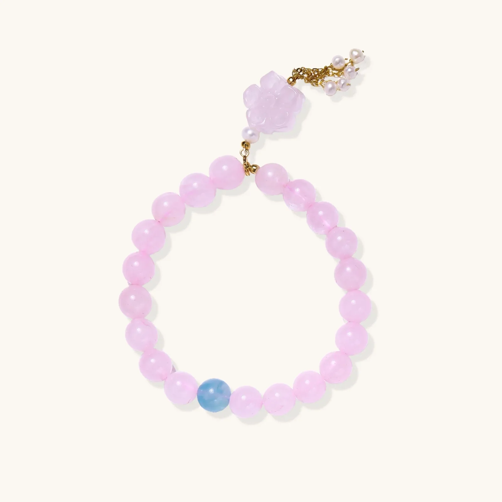 Stretchy beaded bracelet with pink rose quartz, blue aquamarine, carved floral pendant, and pearl tassel clasp.