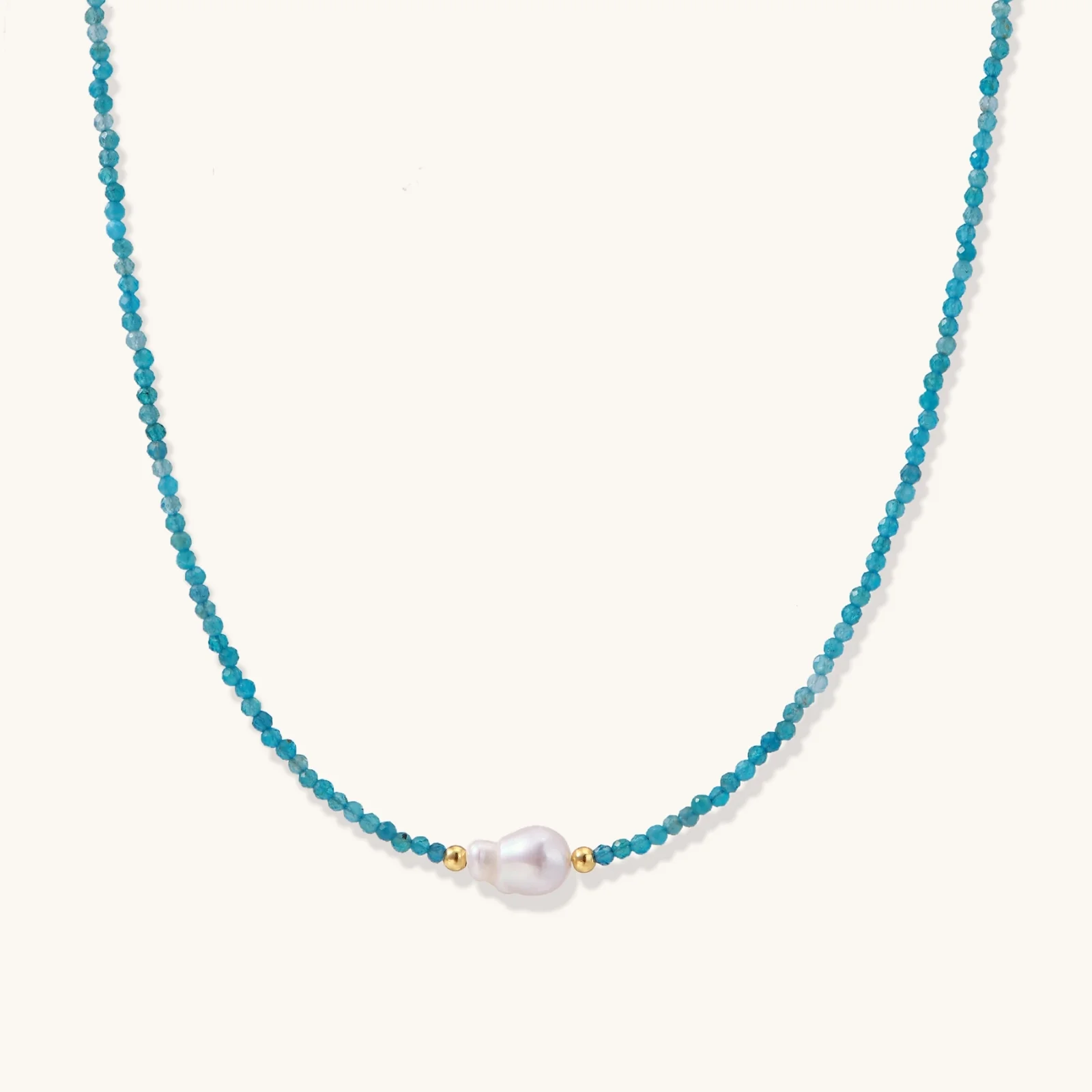 Delicate gold vermeil necklace with teal apatite beads and freshwater pearl on white background.