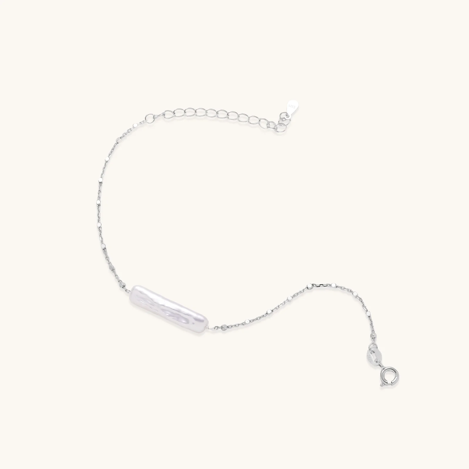 Minimalist bracelet with iridescent baroque pearl on rhodium-plated sterling silver chain against cream background