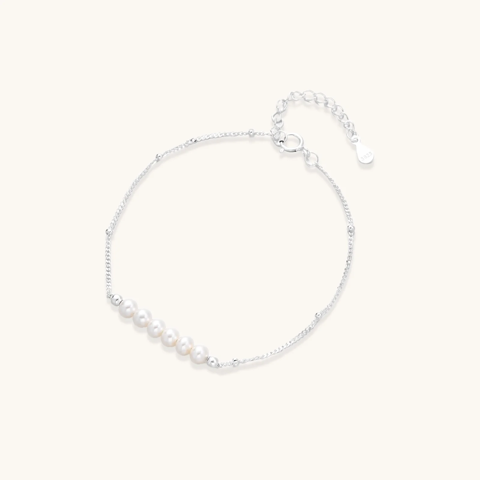 Delicate rhodium-plated silver chain bracelet with row of small baroque pearls centered on white background.