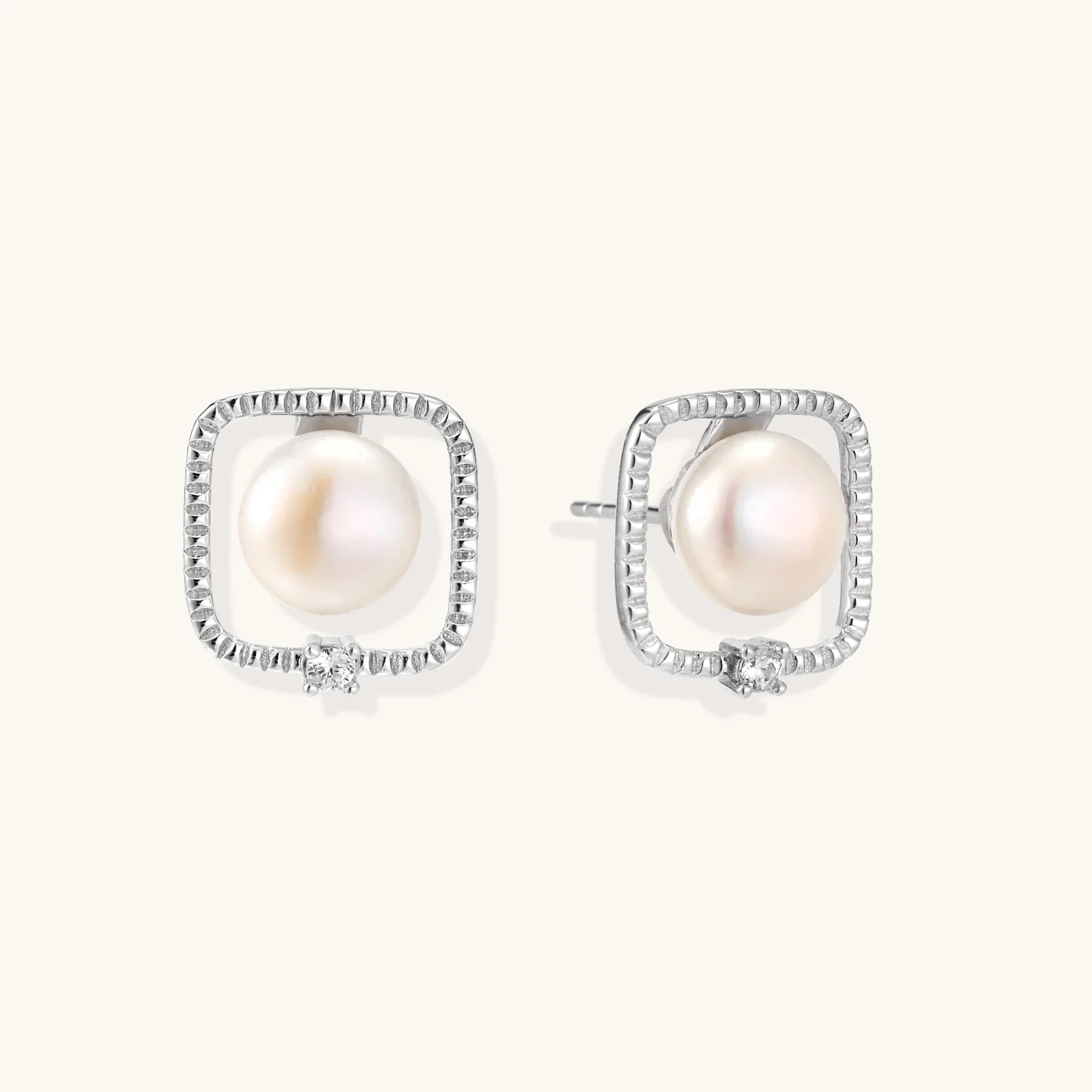 Rhodium-plated silver stud earrings with cushion frame, centered freshwater pearl, and tiny crystal accent