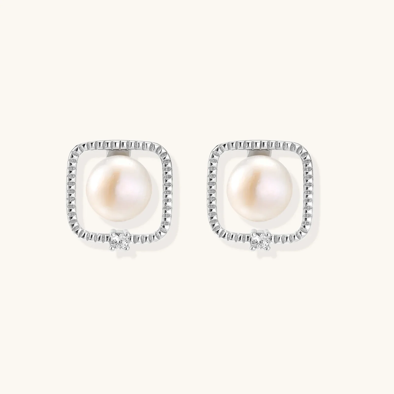 Rhodium-plated silver stud earrings with cushion frame, centered freshwater pearl, and tiny crystal accent