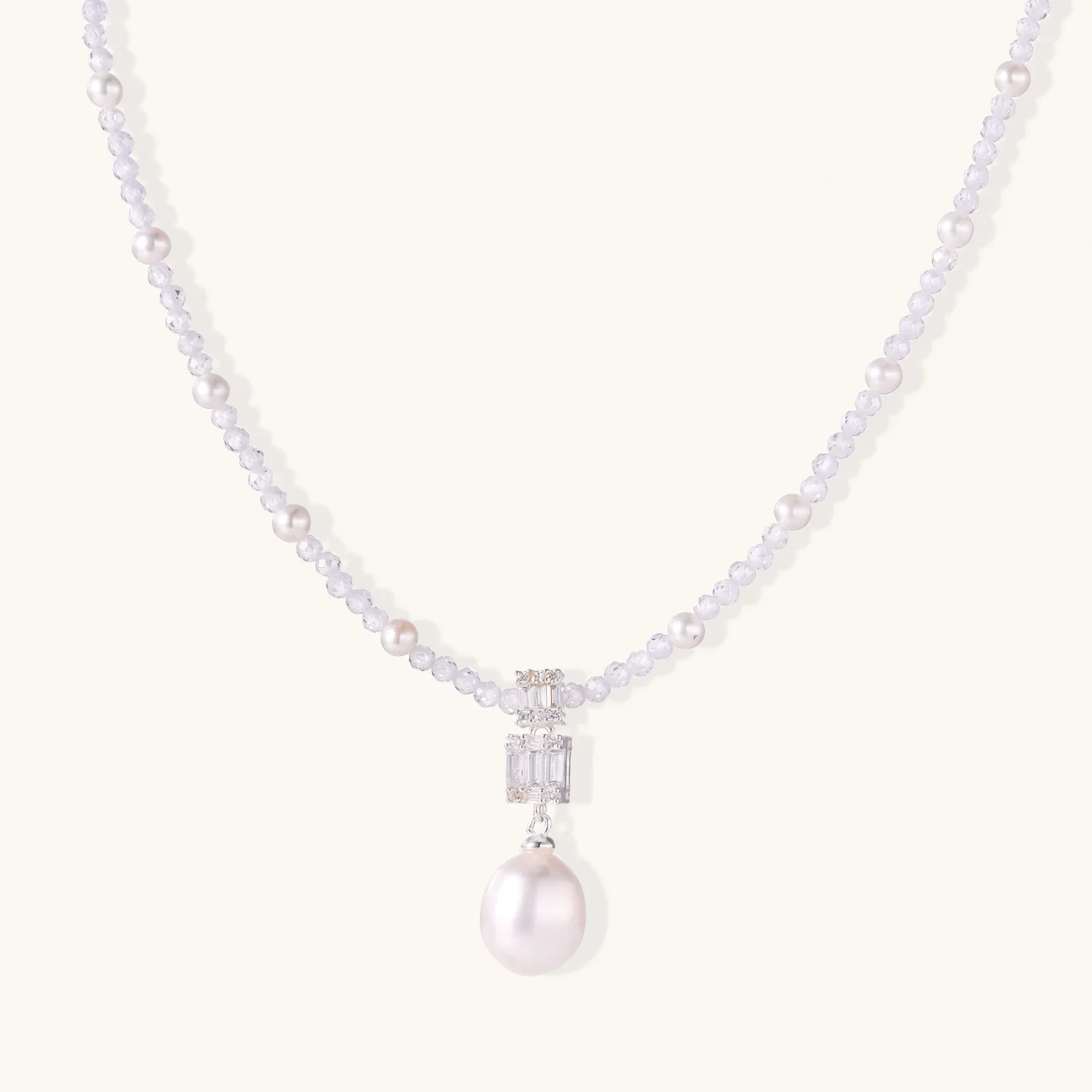 Dainty necklace with lavender crystal beads, freshwater pearls, geometric pendant, and large pearl drop on white background.