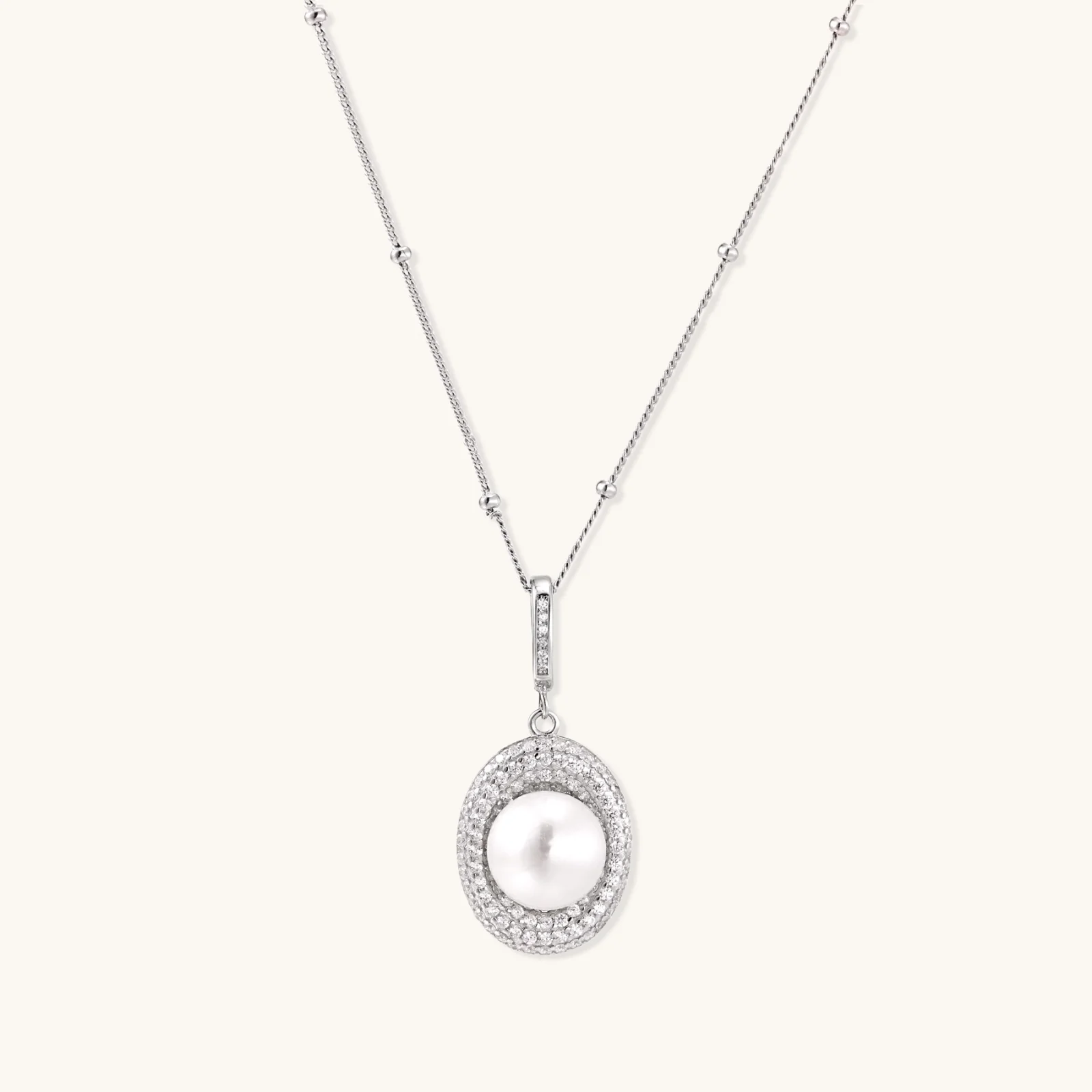 Oval sterling silver pendant with crystal halo surrounding a white freshwater pearl on delicate chain