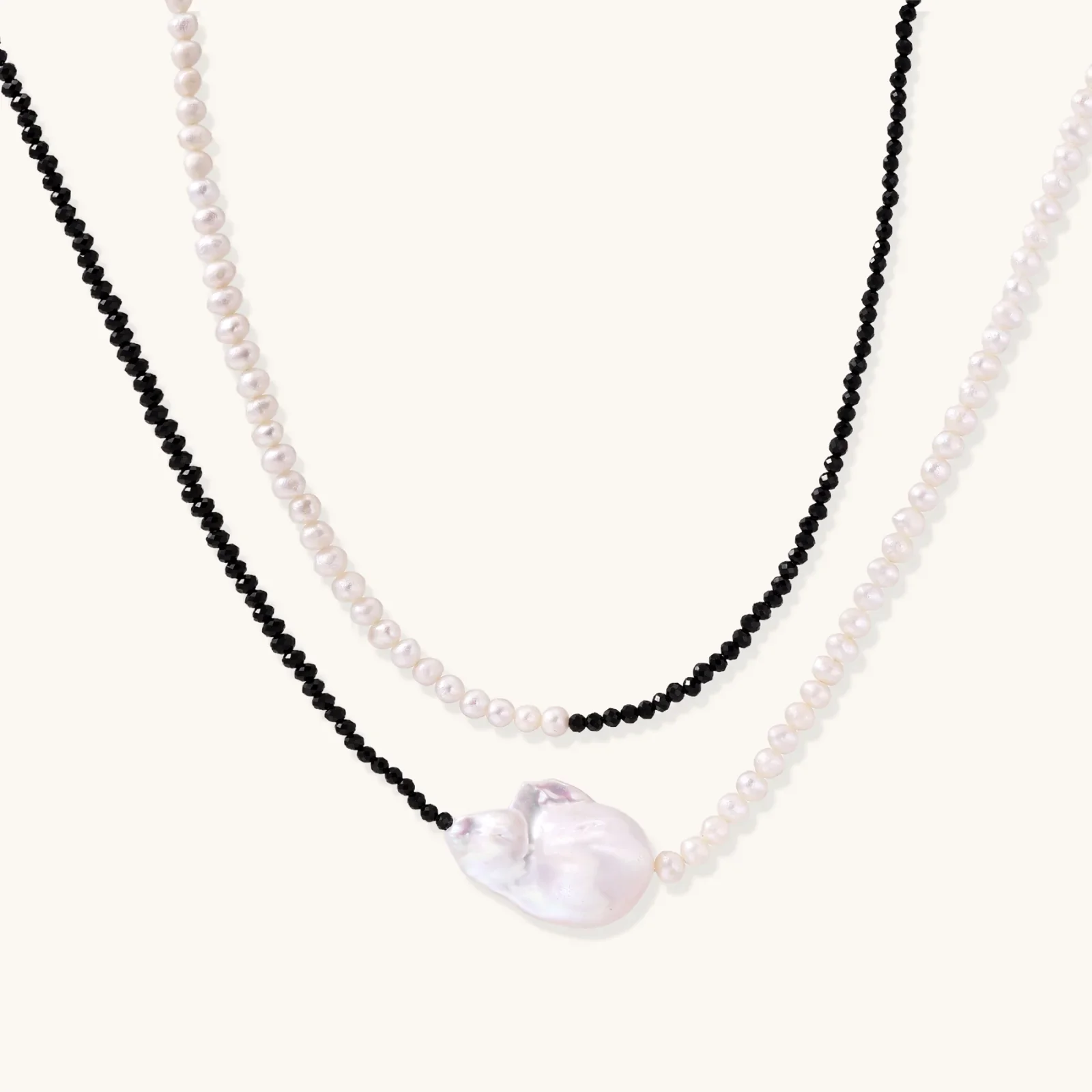 Double-strand necklace with black faceted quartz and white pearls featuring an oversized baroque pearl centerpiece