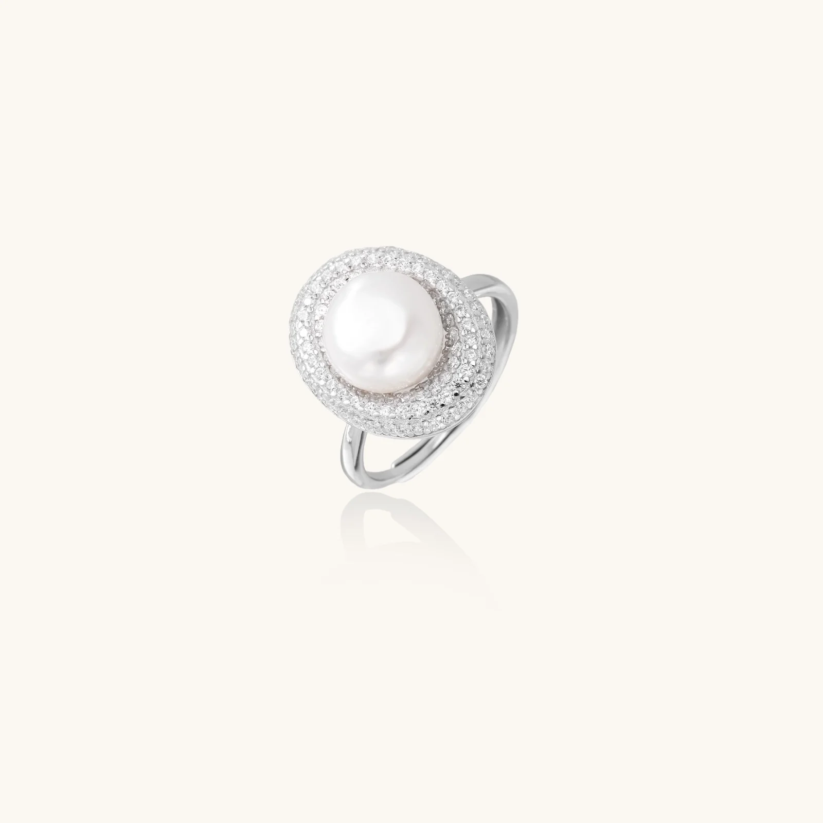 Silver ring with lustrous white pearl center surrounded by sparkling crystal halo on light background.