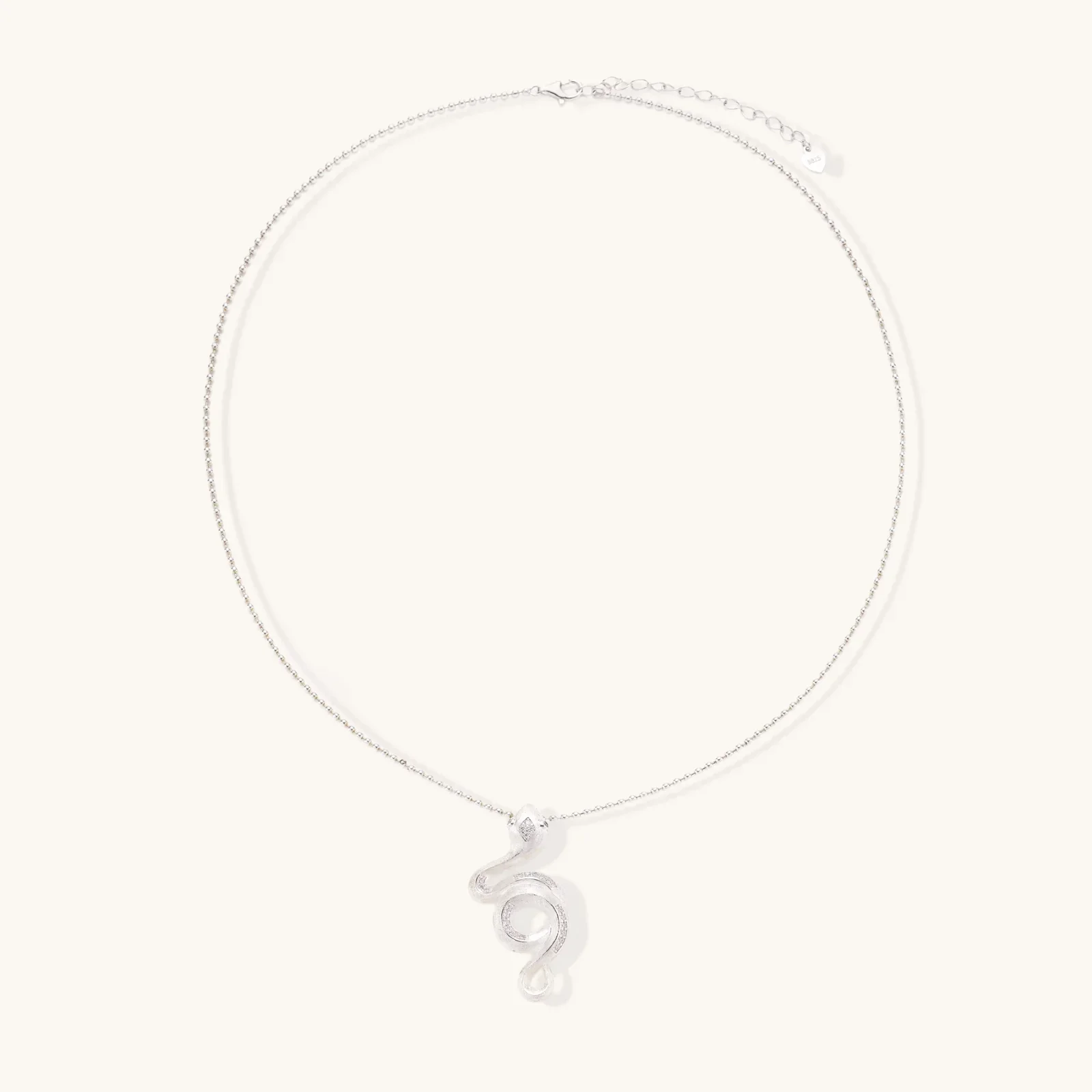 Abstract S-curve sterling silver pendant with zirconia accents on delicate chain against white background