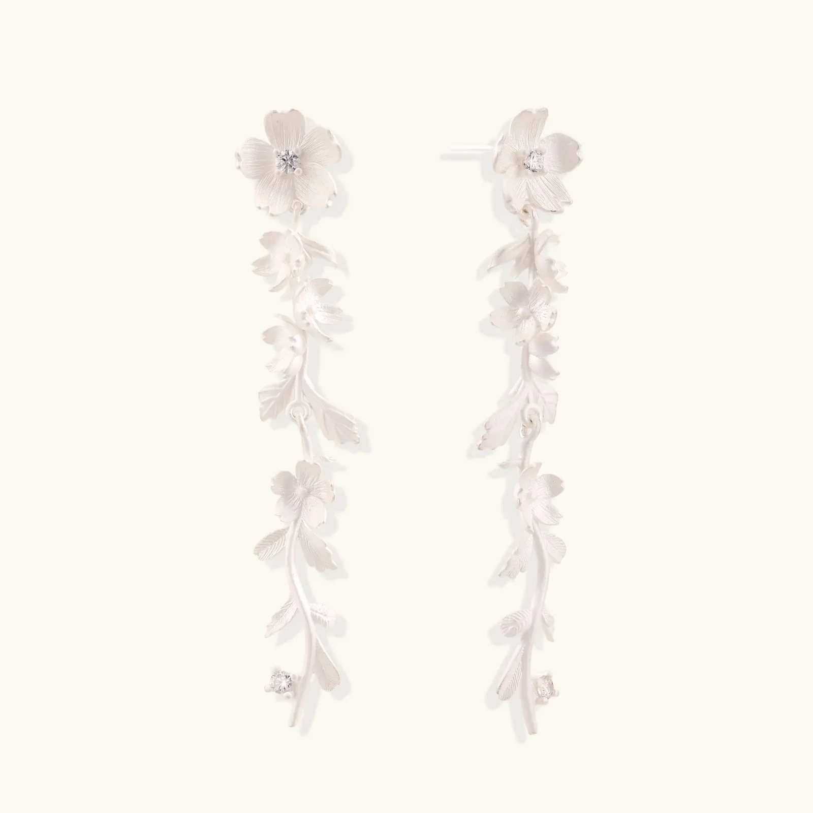 Long sterling silver drop earrings with delicate floral vine design and crystal accents on white background