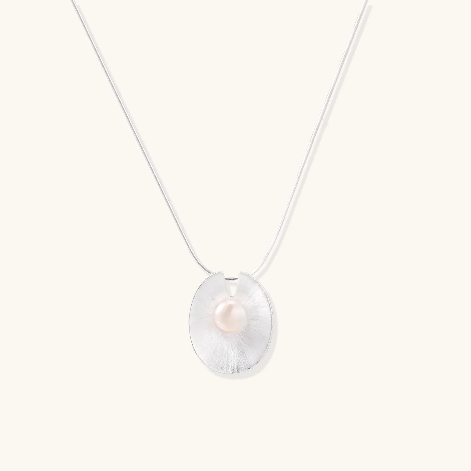 Sterling silver disc necklace with textured finish and centered freshwater pearl on delicate chain