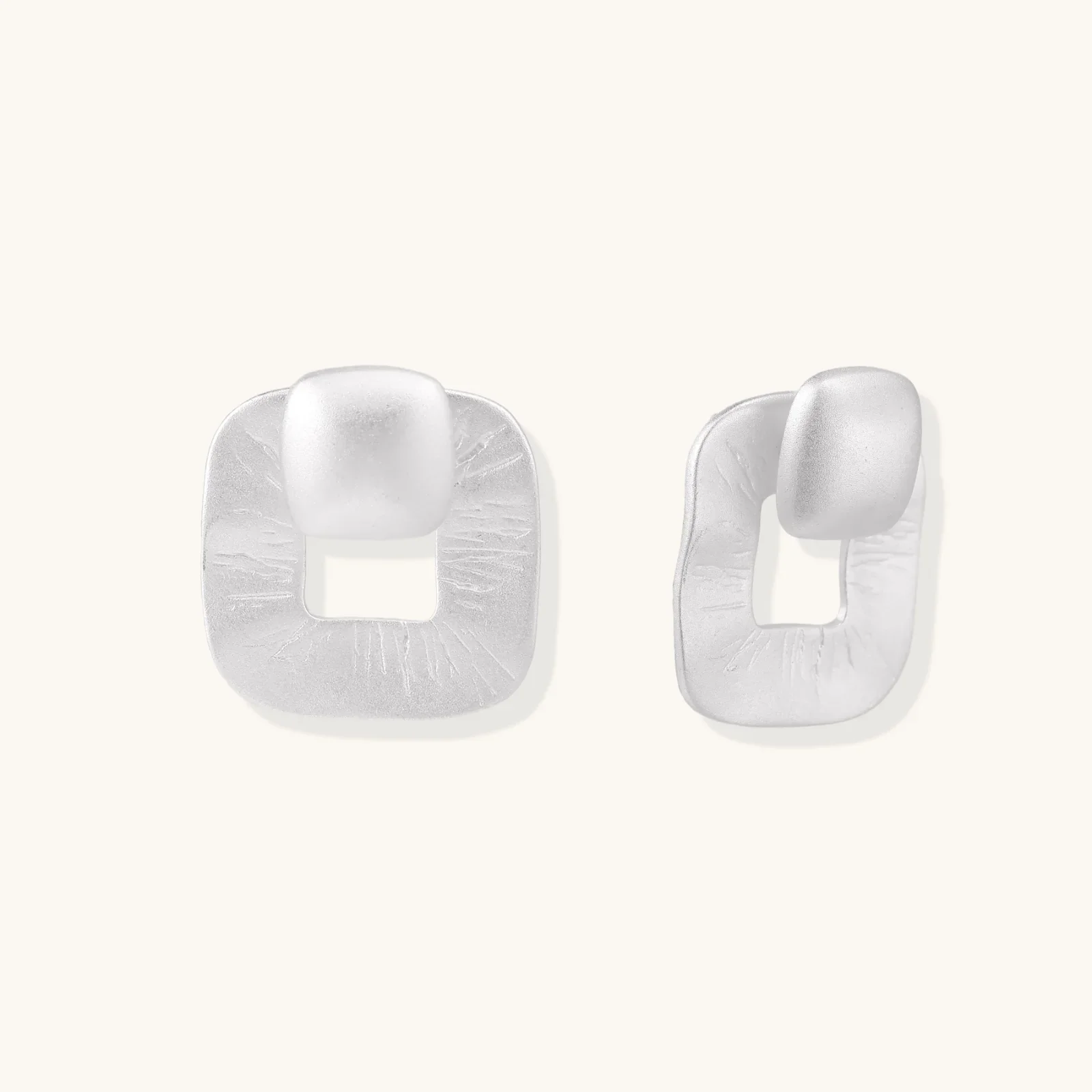 Pair of geometric sterling silver earrings with frosted square frames and glossy rounded studs on white background