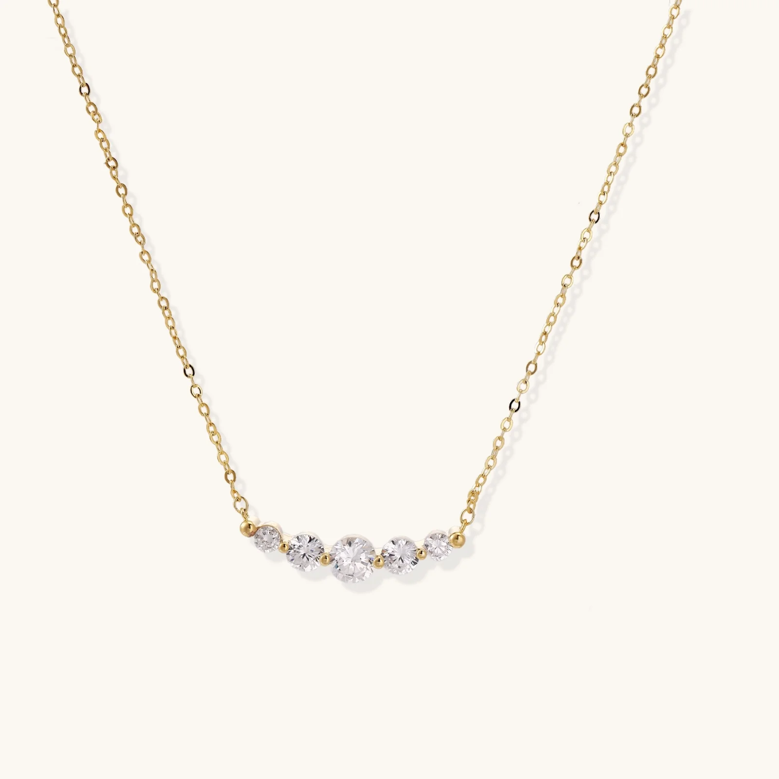 Delicate 14K gold-plated necklace with five graduated zirconia stones arranged in a curved arc on fine chain