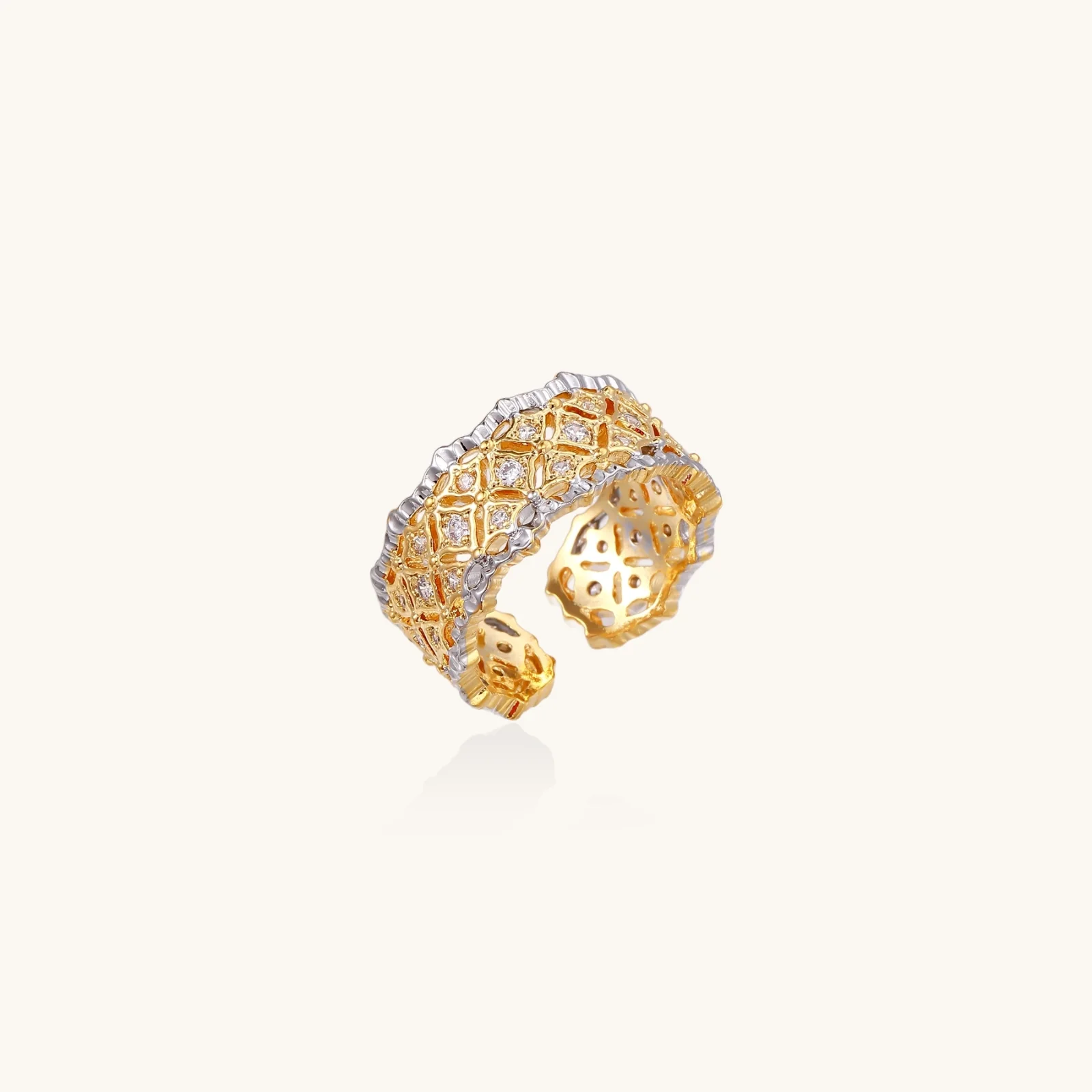 Two-tone ring with geometric lattice pattern in gold and silver finish with crystal accents on beige background