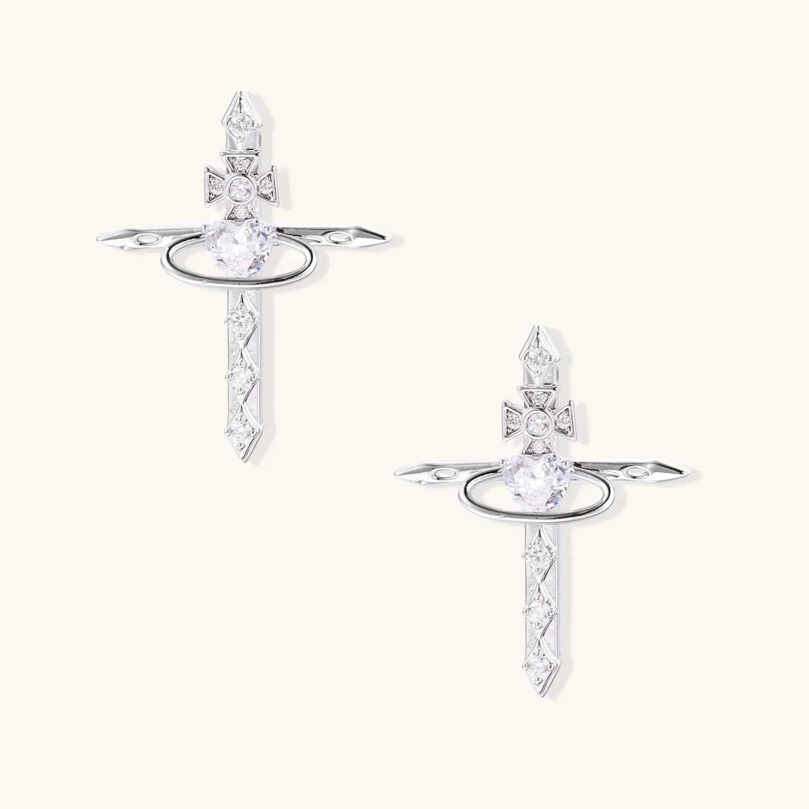 White gold plated cross earrings with orbital ring & zirconia stones on cream background