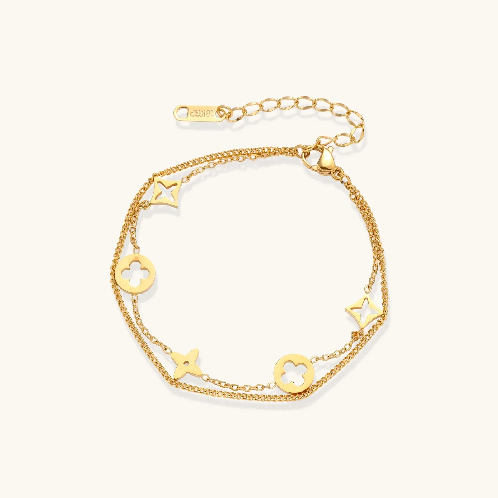 Double-layer gold-plated bracelet with quatrefoil and star charms on cream background, 18K gold finish.