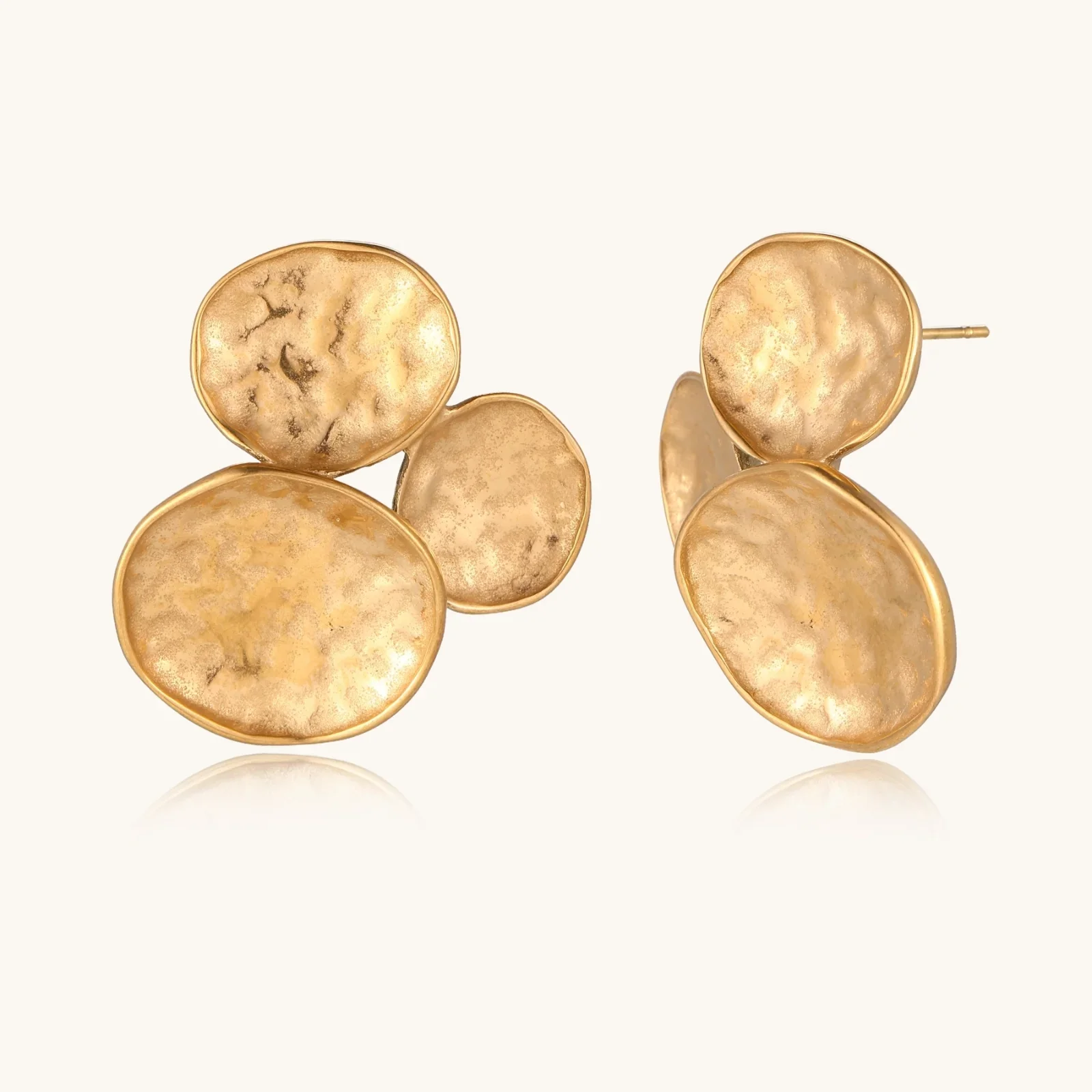 Three hammered gold discs clustered together forming organic statement earrings with textured surfaces