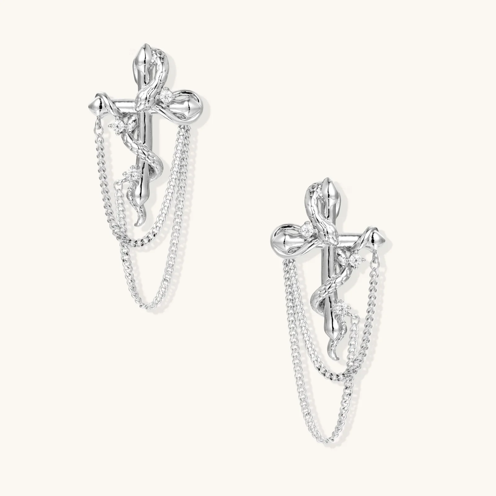 Sculptural white gold bow earrings with cascading chain details on neutral background