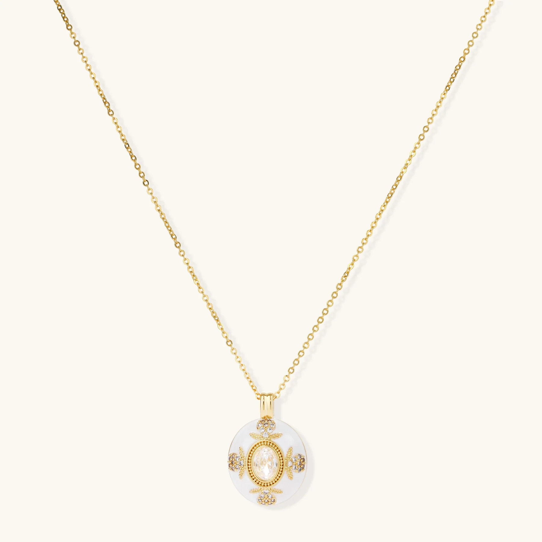 Gold-plated necklace with circular white enamel pendant featuring central zirconia stone and ornate decorative details