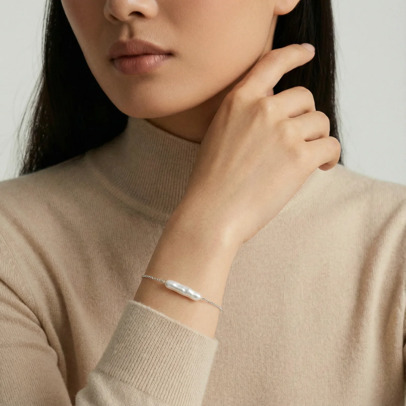 Minimalist bracelet with iridescent baroque pearl on rhodium-plated sterling silver chain against cream background