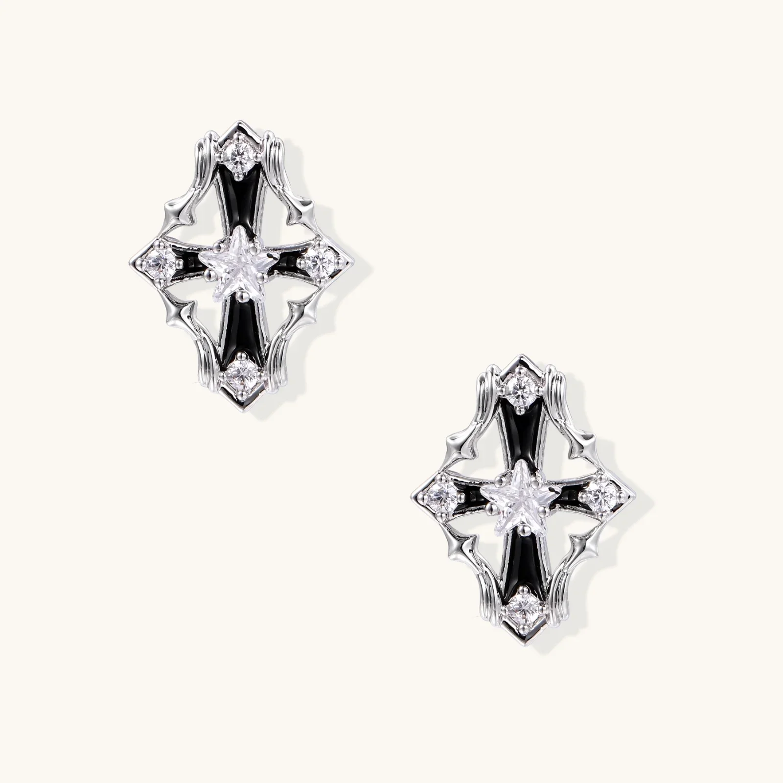 Pair of Art Deco-style stud earrings with star crystals, black enamel accents, and white gold plating on ivory background.