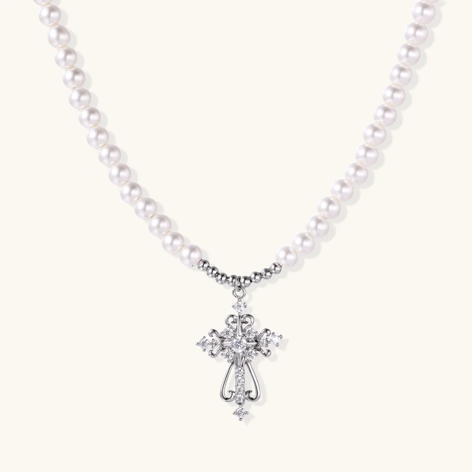 White pearl beaded necklace with ornate crystal-embellished cross pendant on white background, white gold plated finish