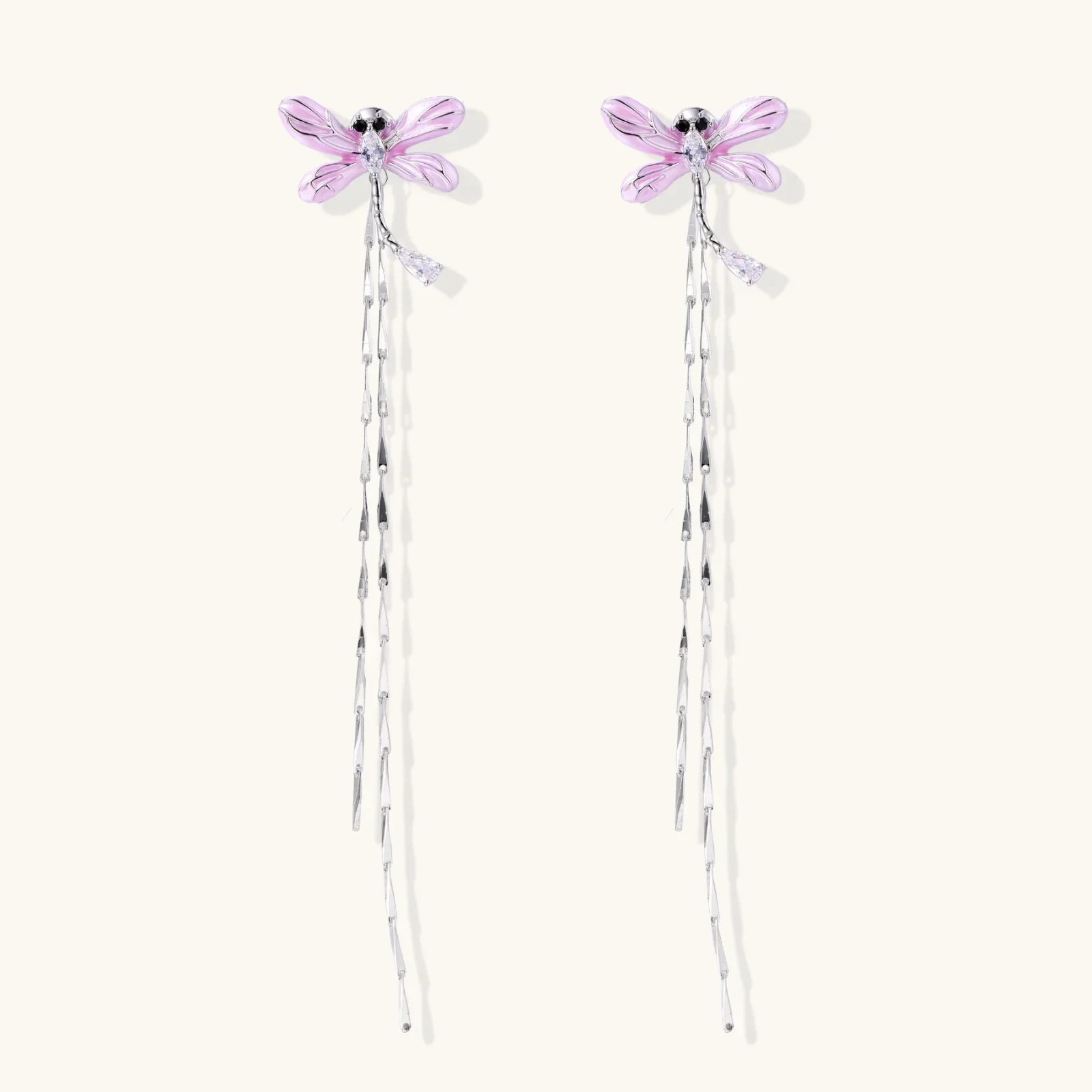 Long drop earrings with translucent lavender enamel dragonfly wings and white gold plated segmented bodies on white background