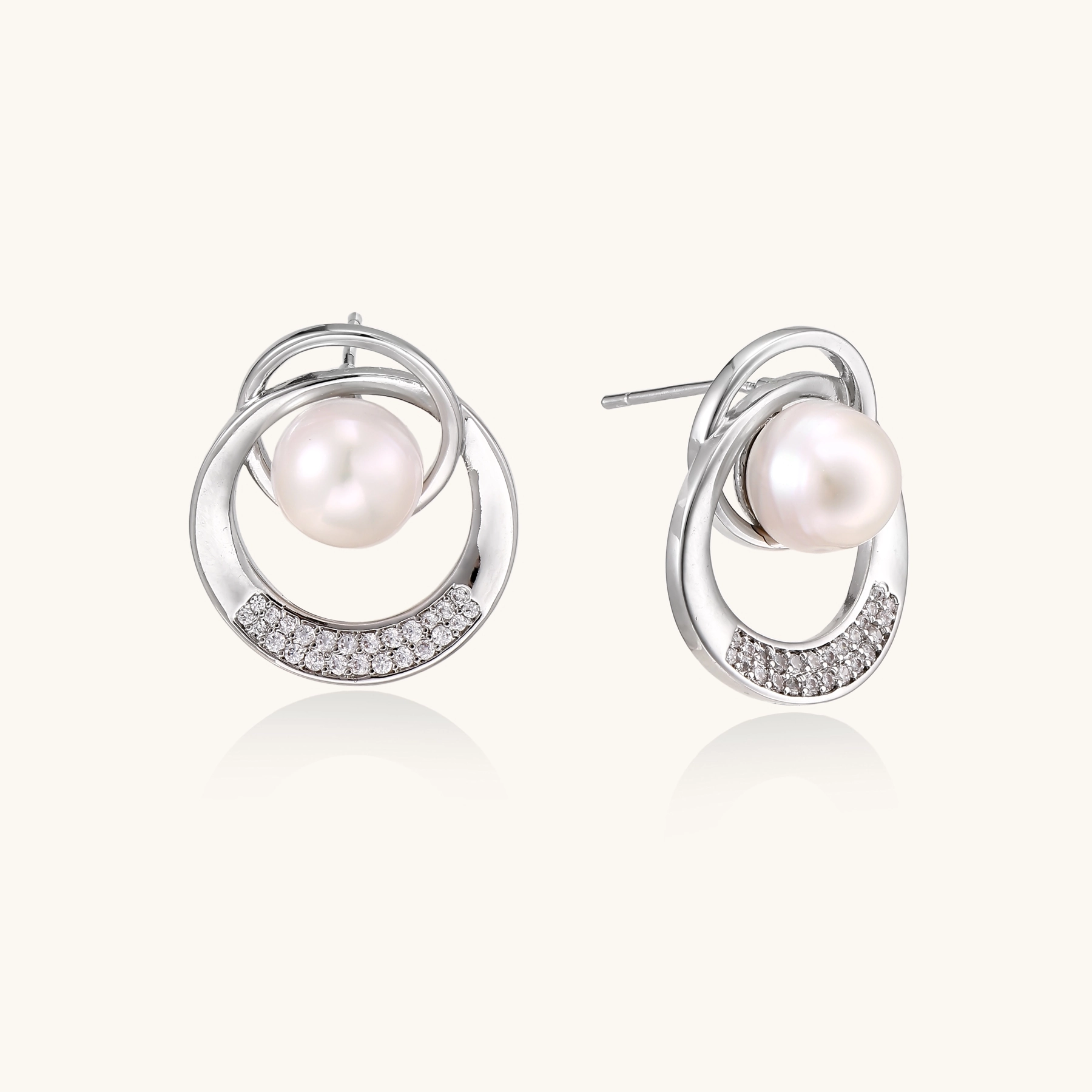 White gold-plated brass earrings with circular design, freshwater pearl center, and diamond accents