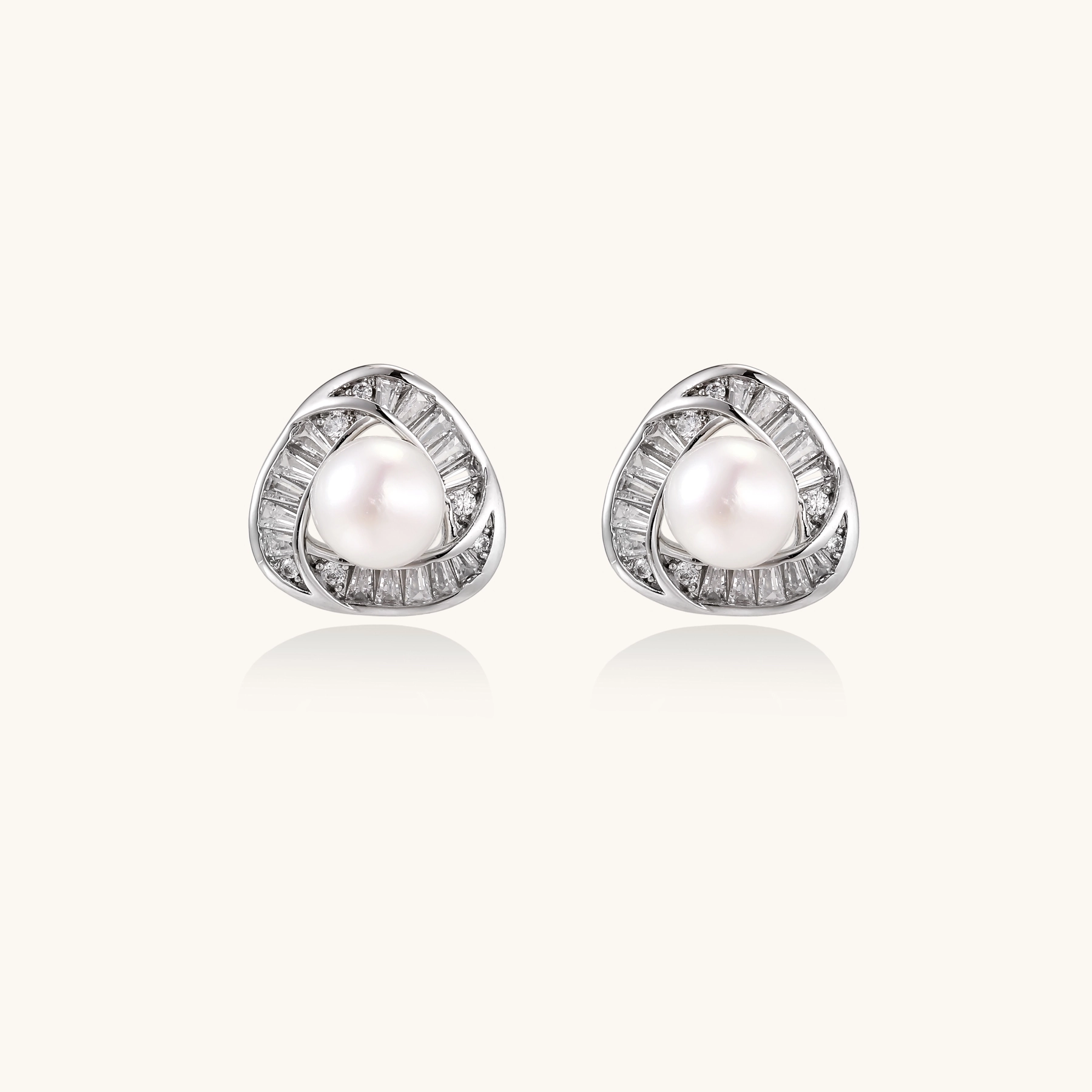 Triangular white gold plated stud earrings with central freshwater pearl and baguette-cut stones on white background